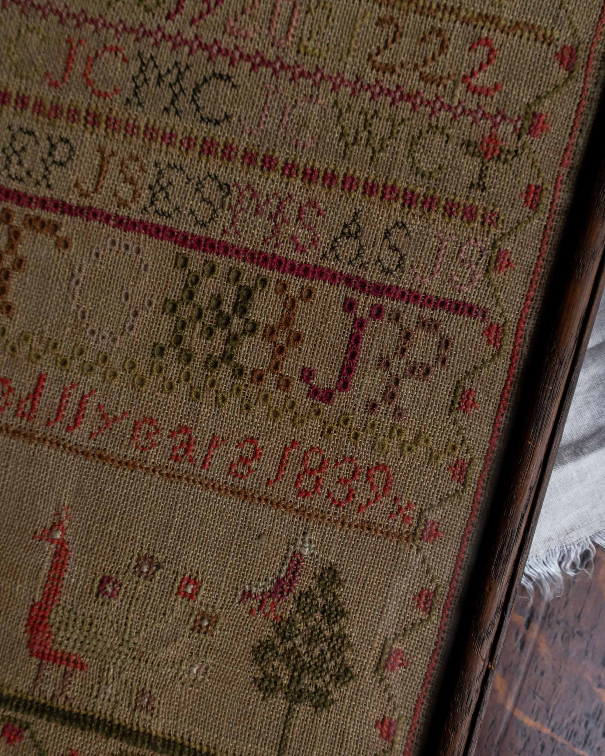 Close-up of a embroidered Scottish sampler with text and patterns, including numbers and letters.