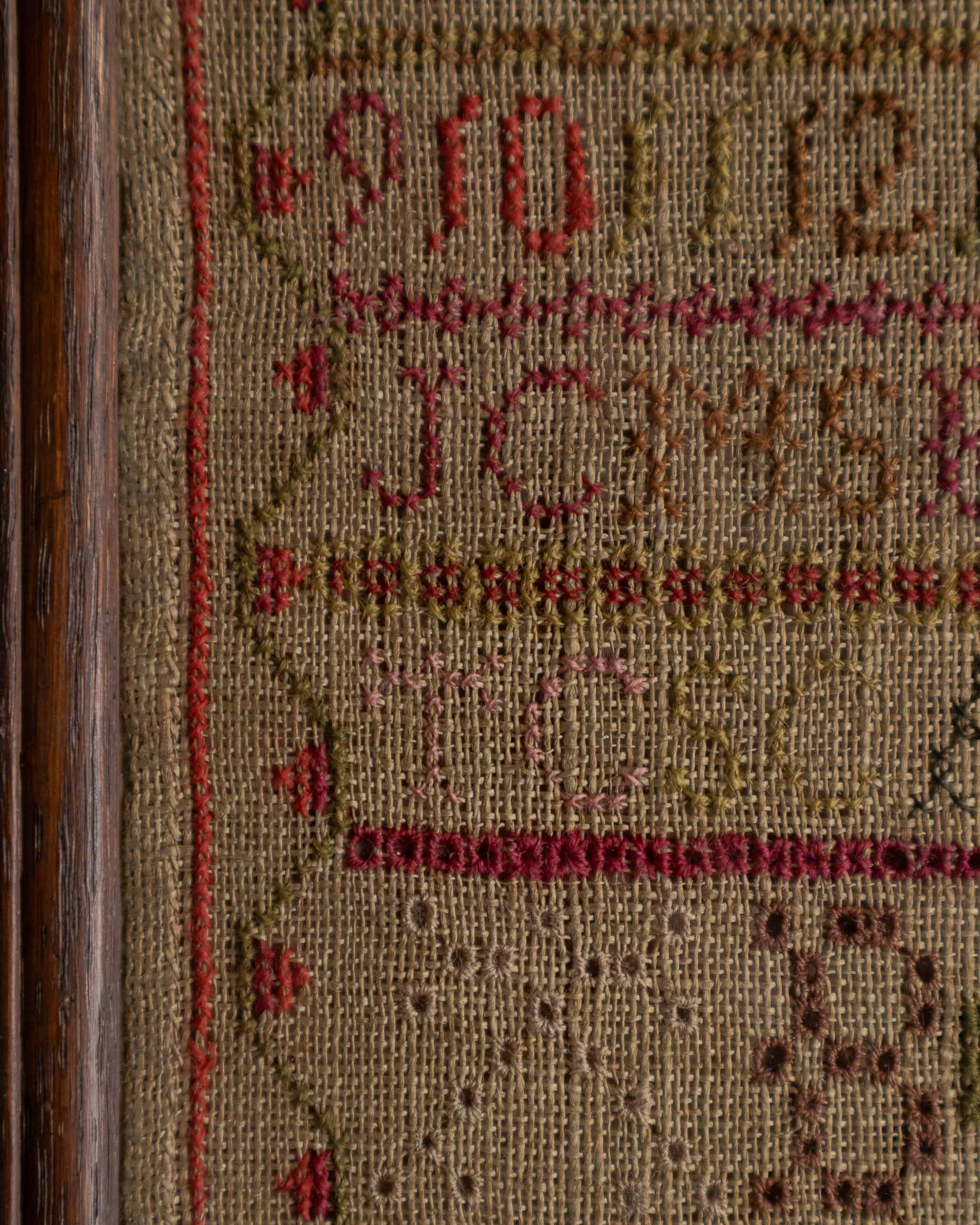 Close-up of a cross-stitched design with numbers and letters on fabric.