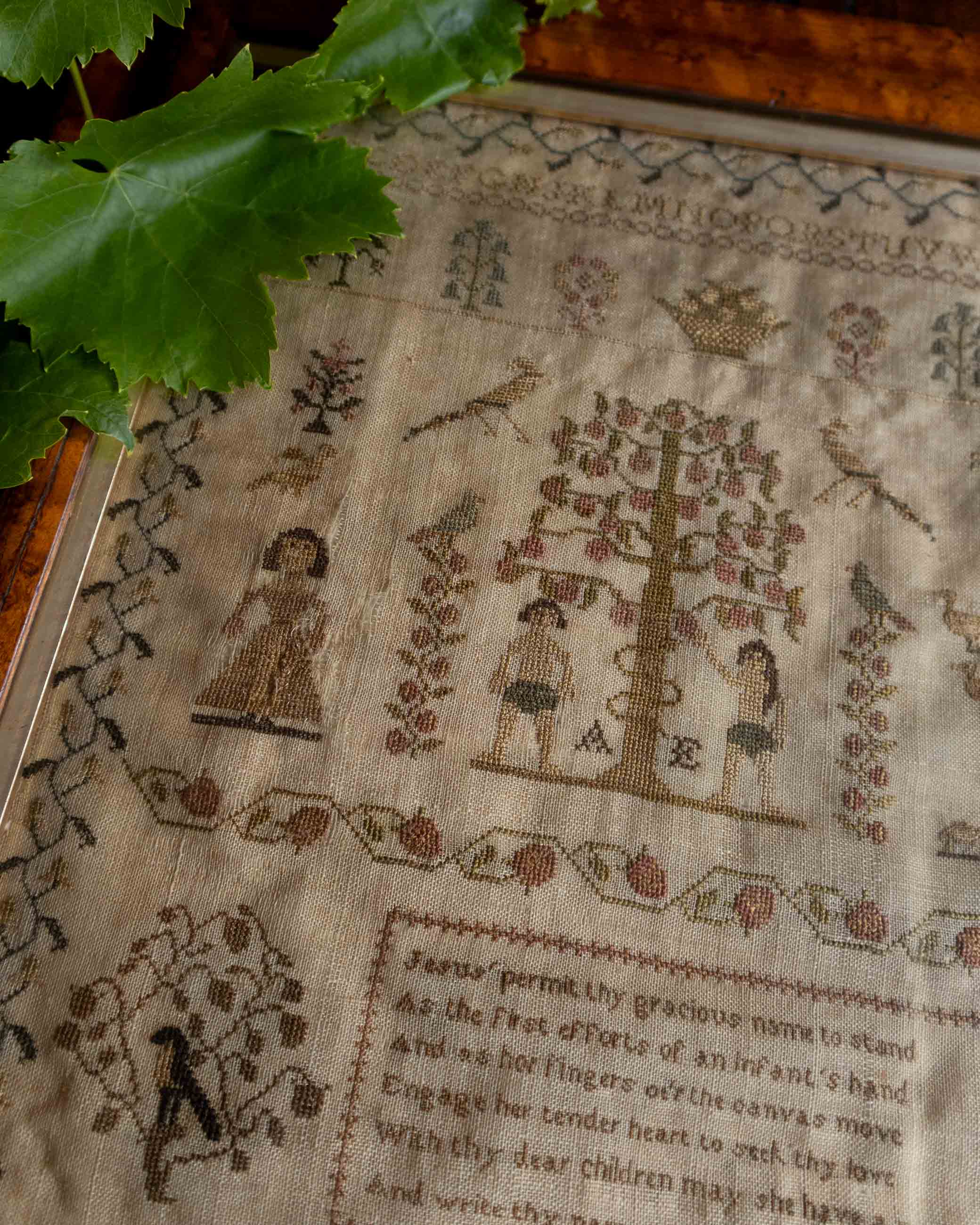 Close-up of a embroidered antique sampler with religious designs and text.