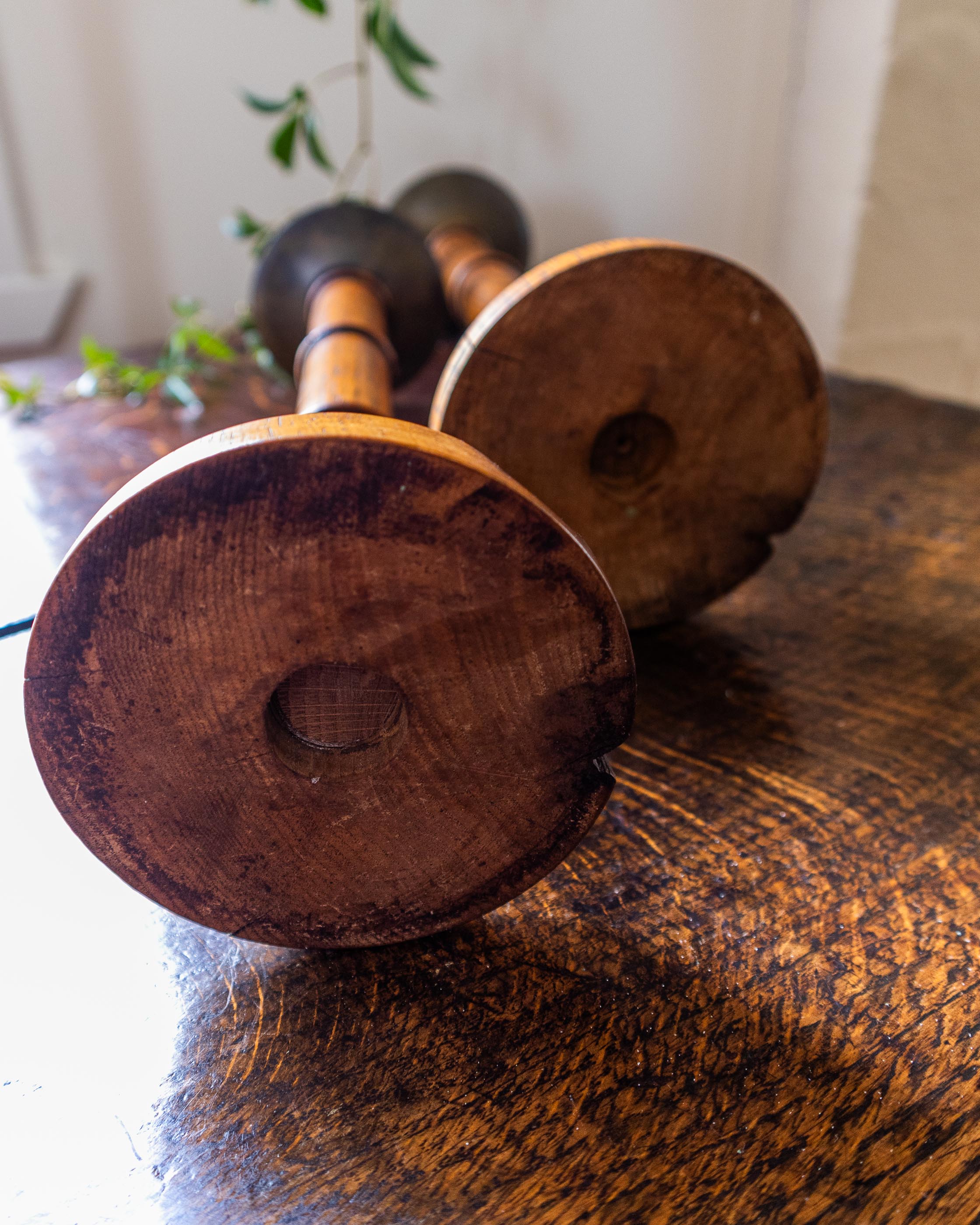 Two wooden candlesticks on a wooden surface with a blurred background