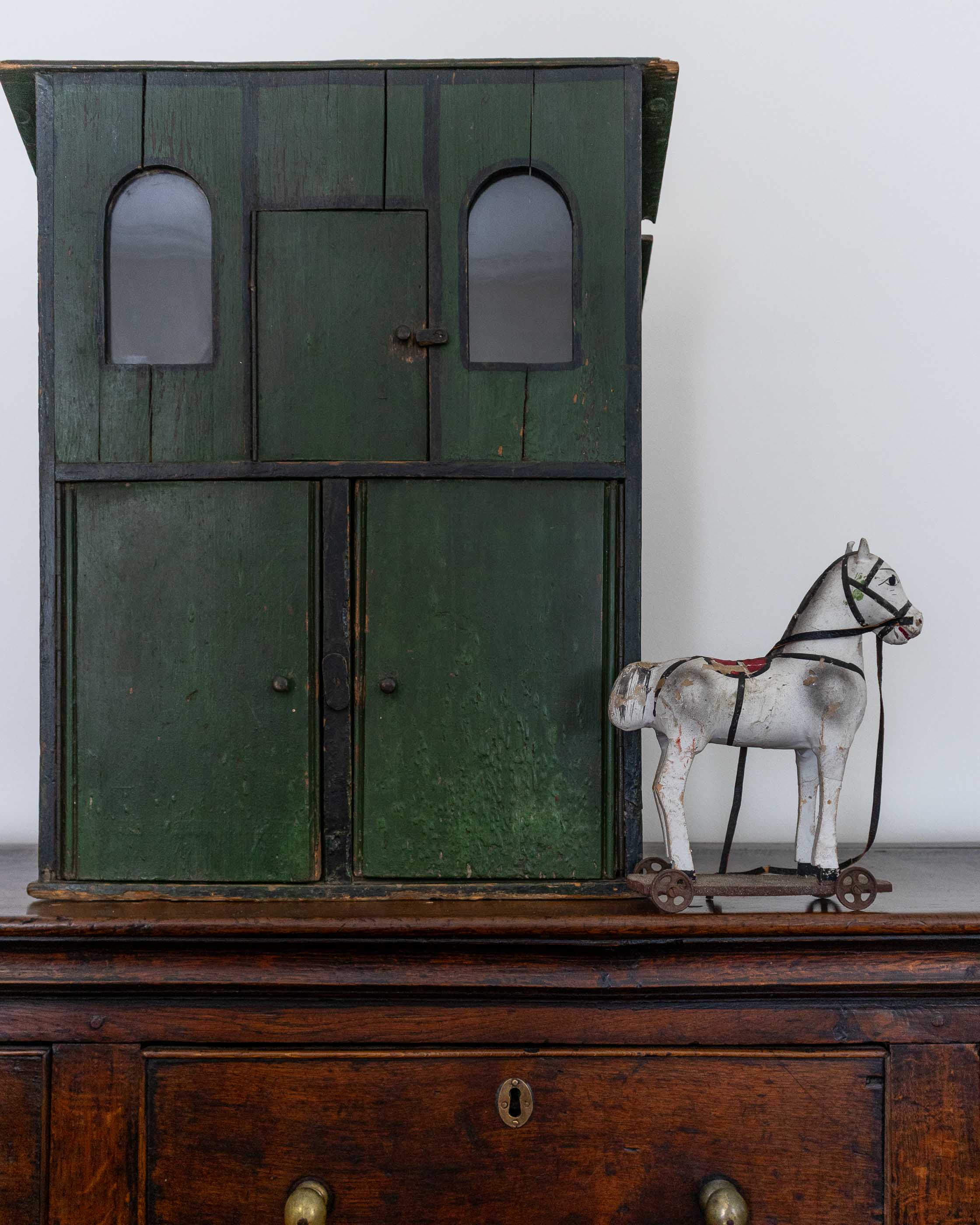 Vintage green cabinet with a toy horse on a wooden surface