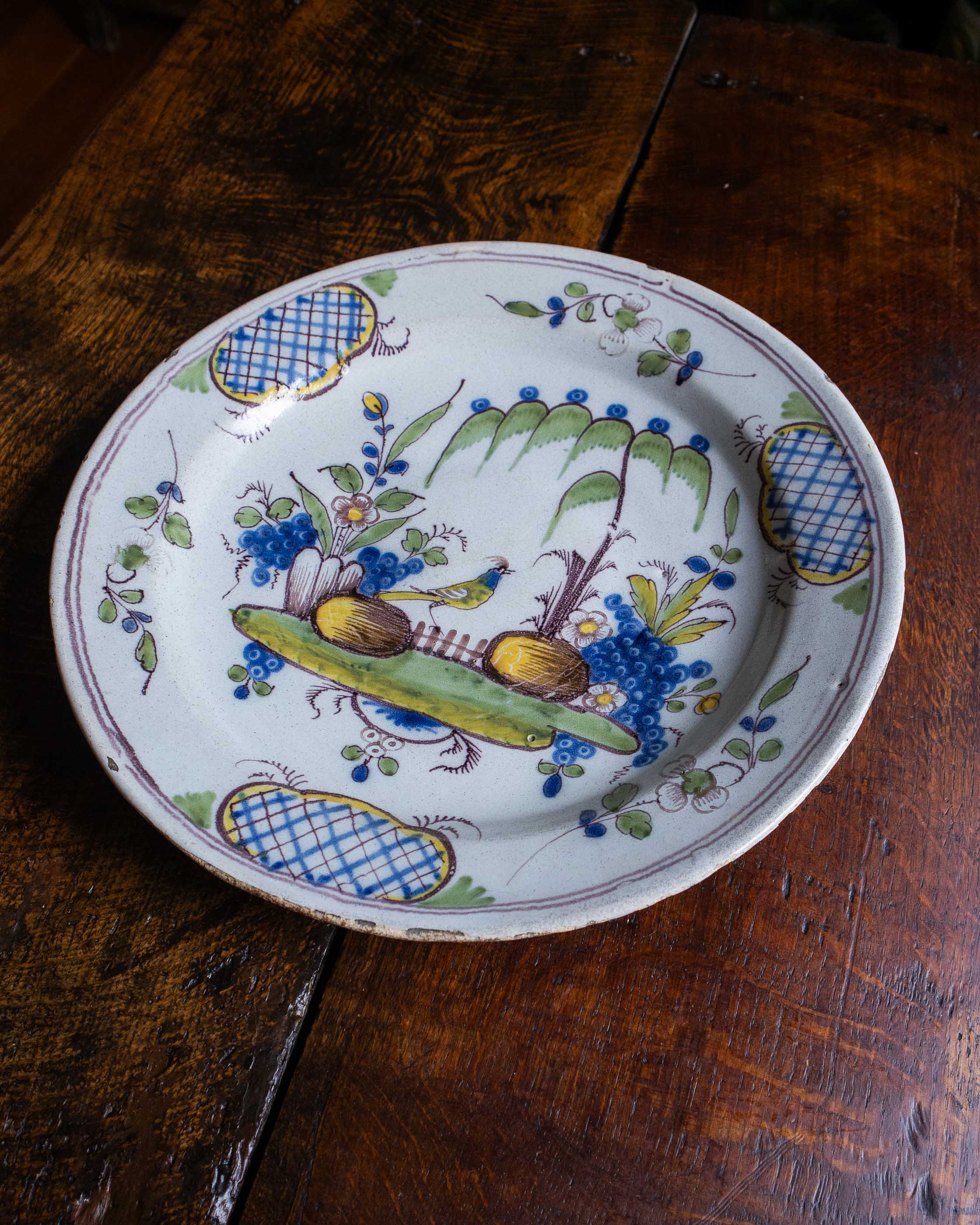 Decorative ceramic plate with floral and fruit design on a wooden surface