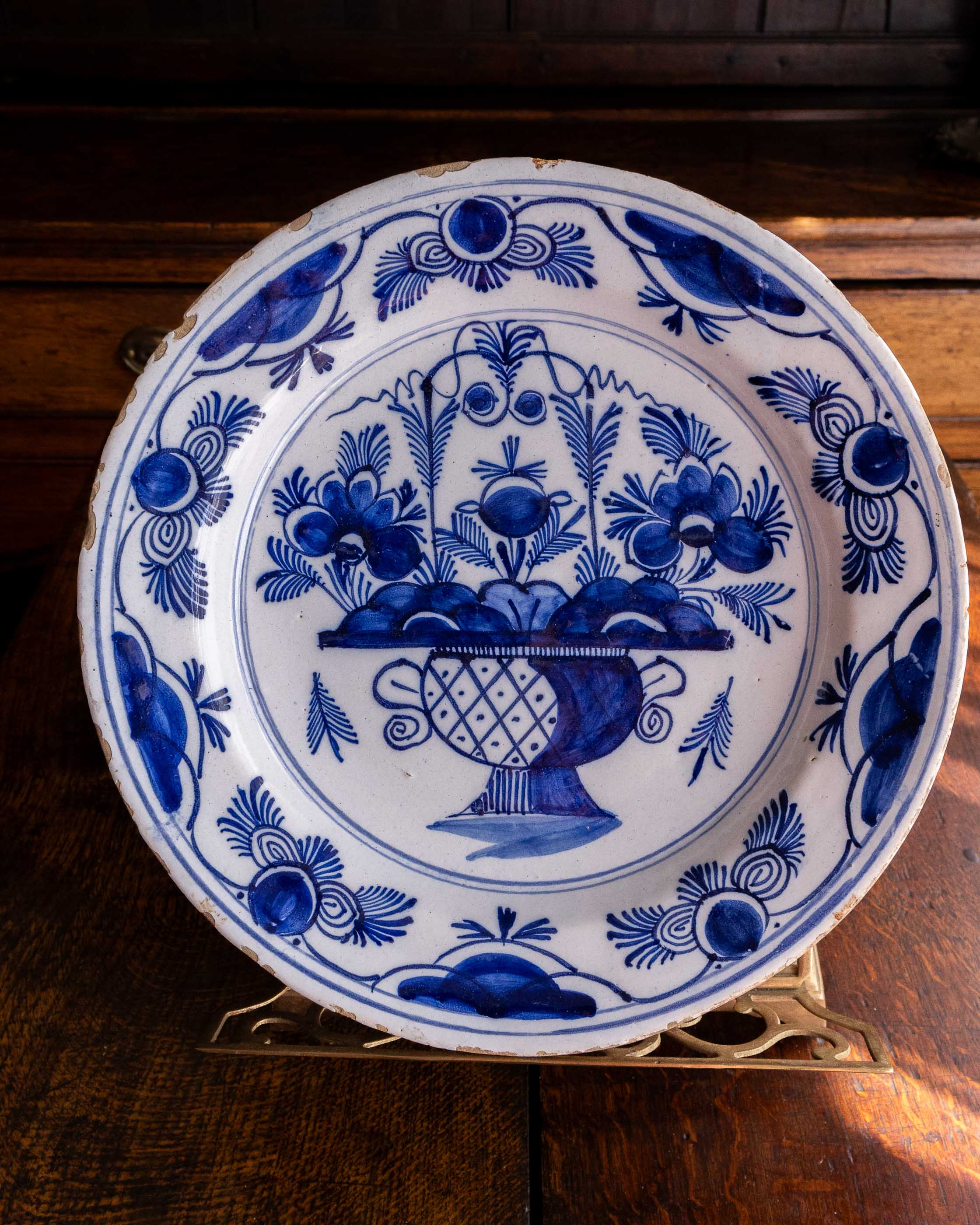 Blue and white decorative plate with floral and fruit design on a wooden surface