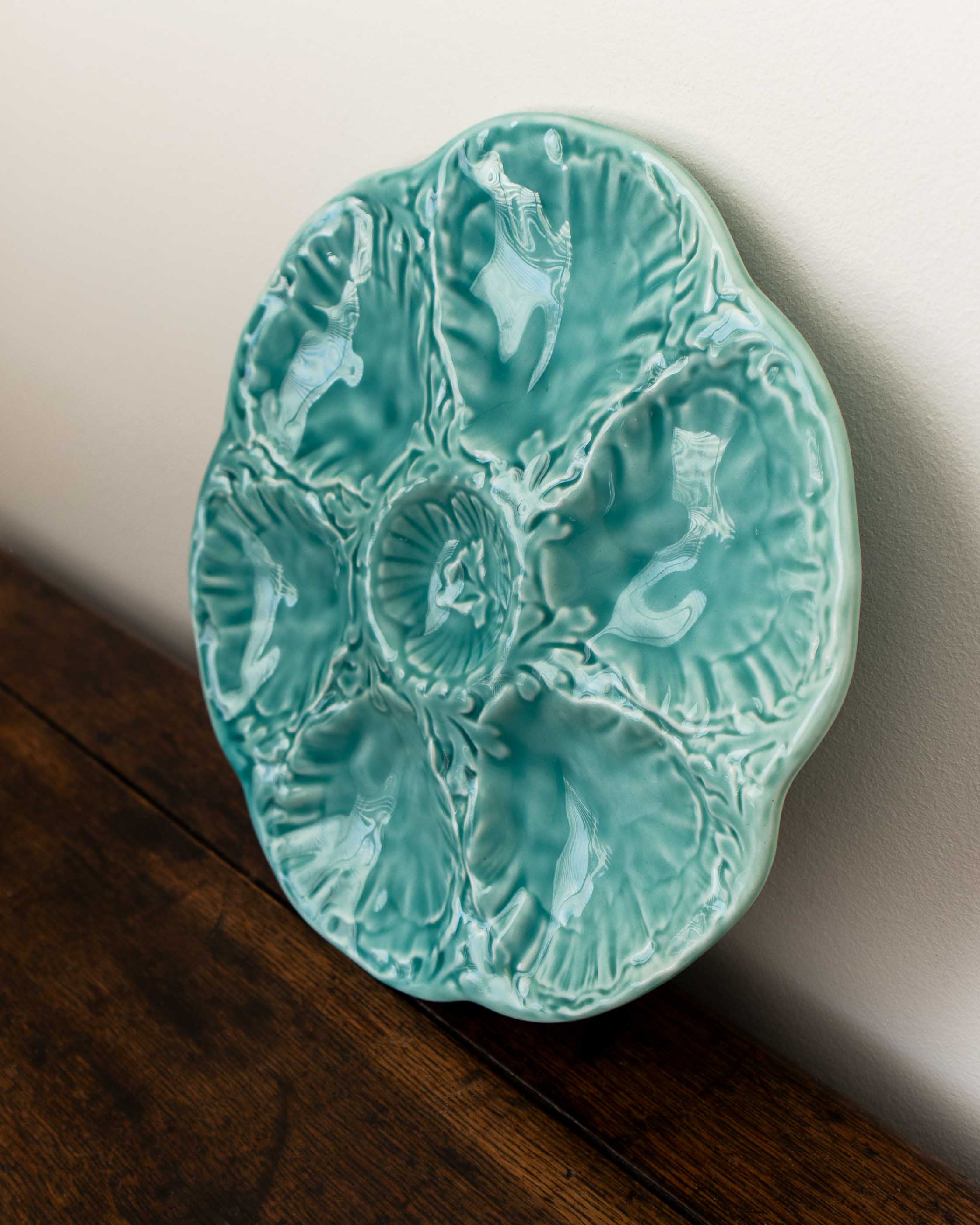 Turquoise ceramic plate with shell design on a wooden surface