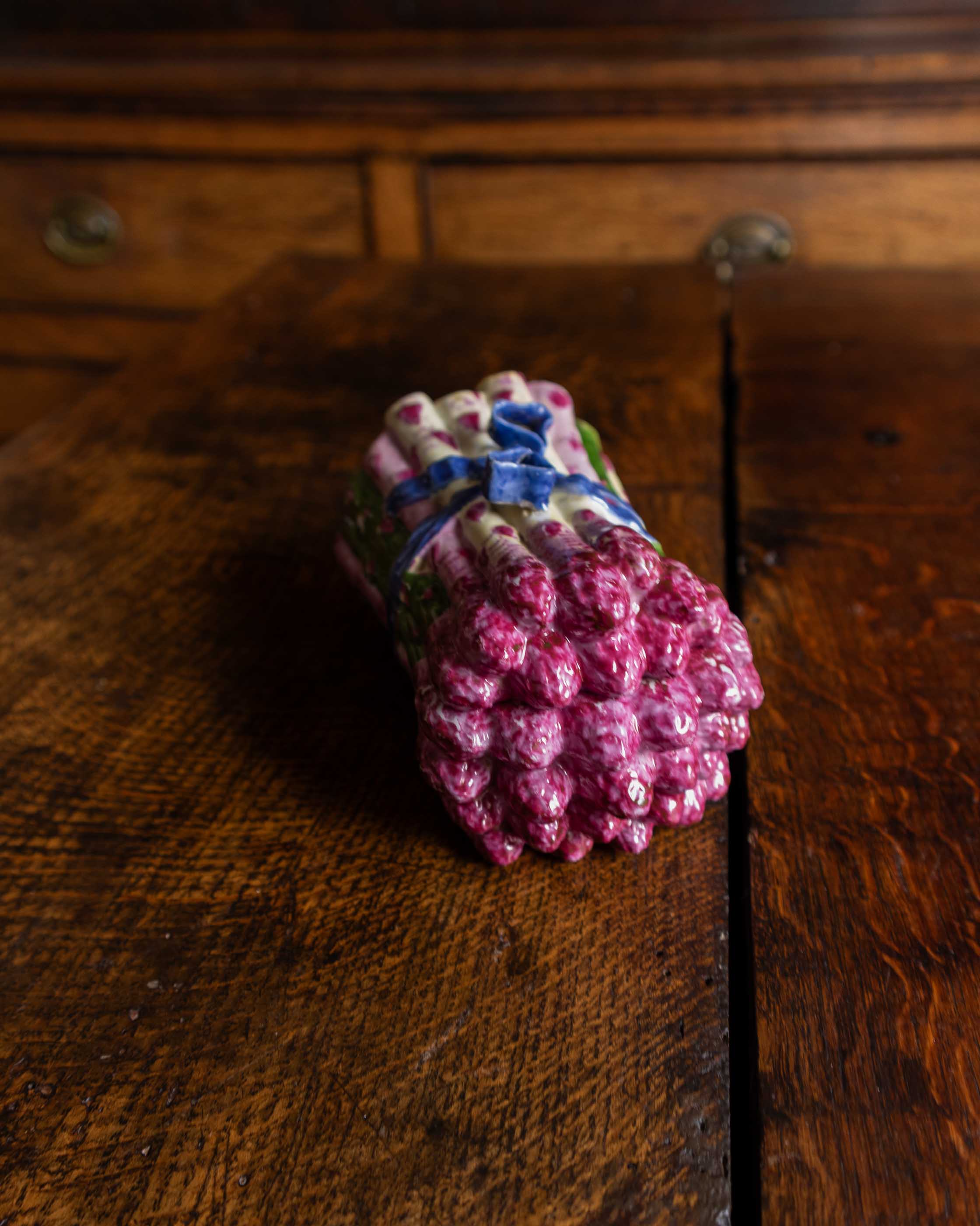 Pink and green and blue ceramic asparagus box on a wooden surface