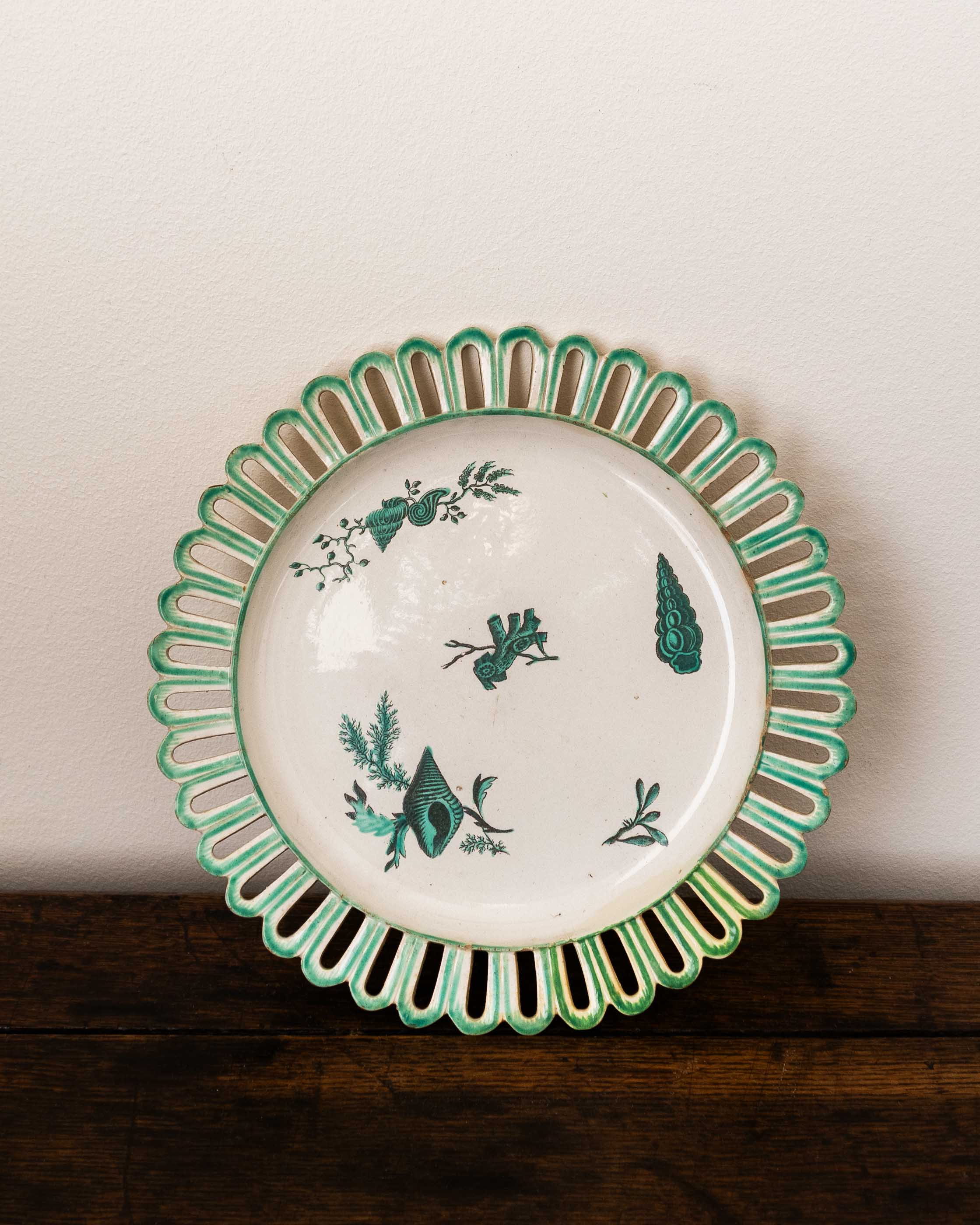 Ceramic plate with decorative green rim and shell patterns on a wooden surface.
