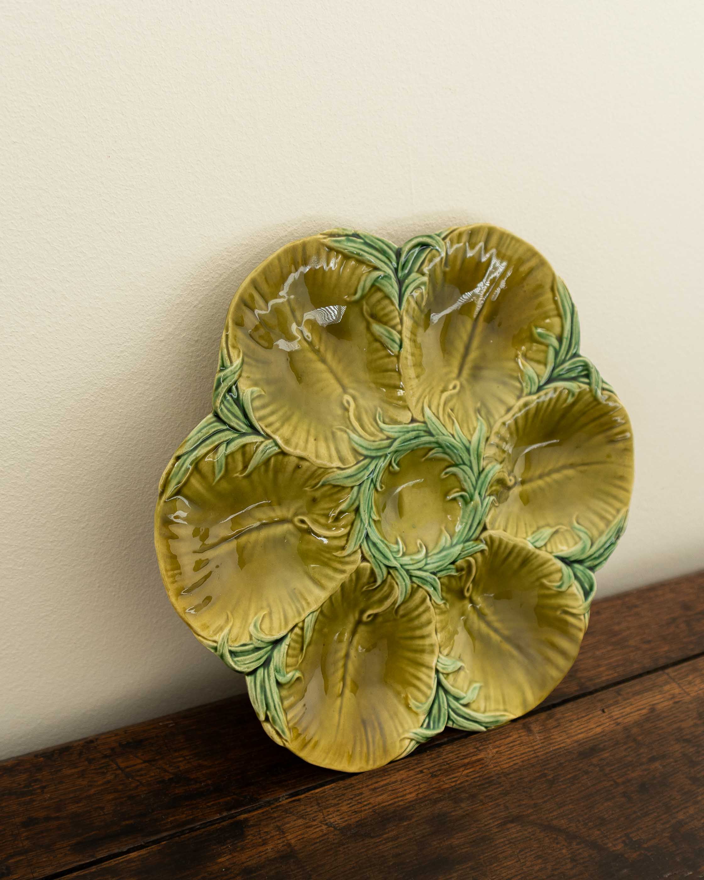 Decorative green oyster plate with green shell patterns on a wooden surface