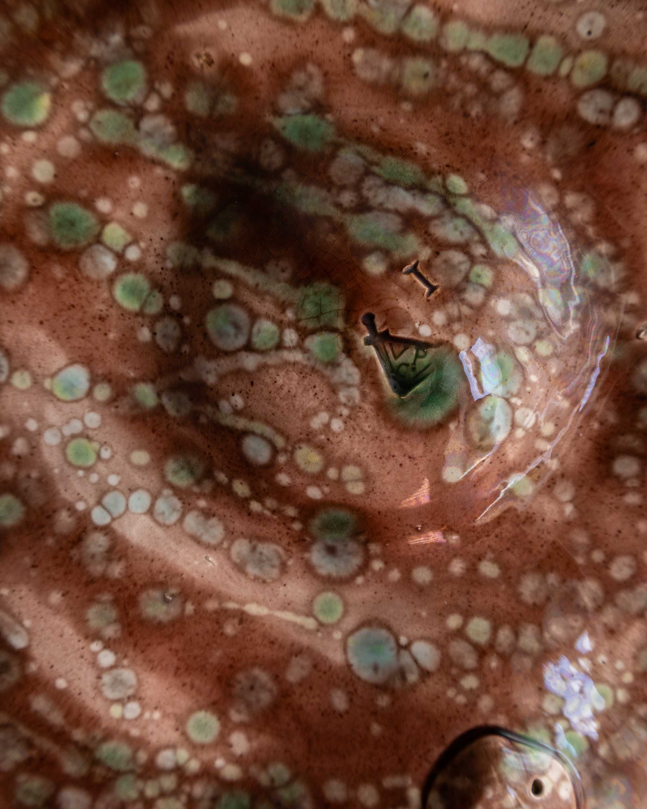 Close-up of a ceramic piece with a spotted surface and visible branding.
