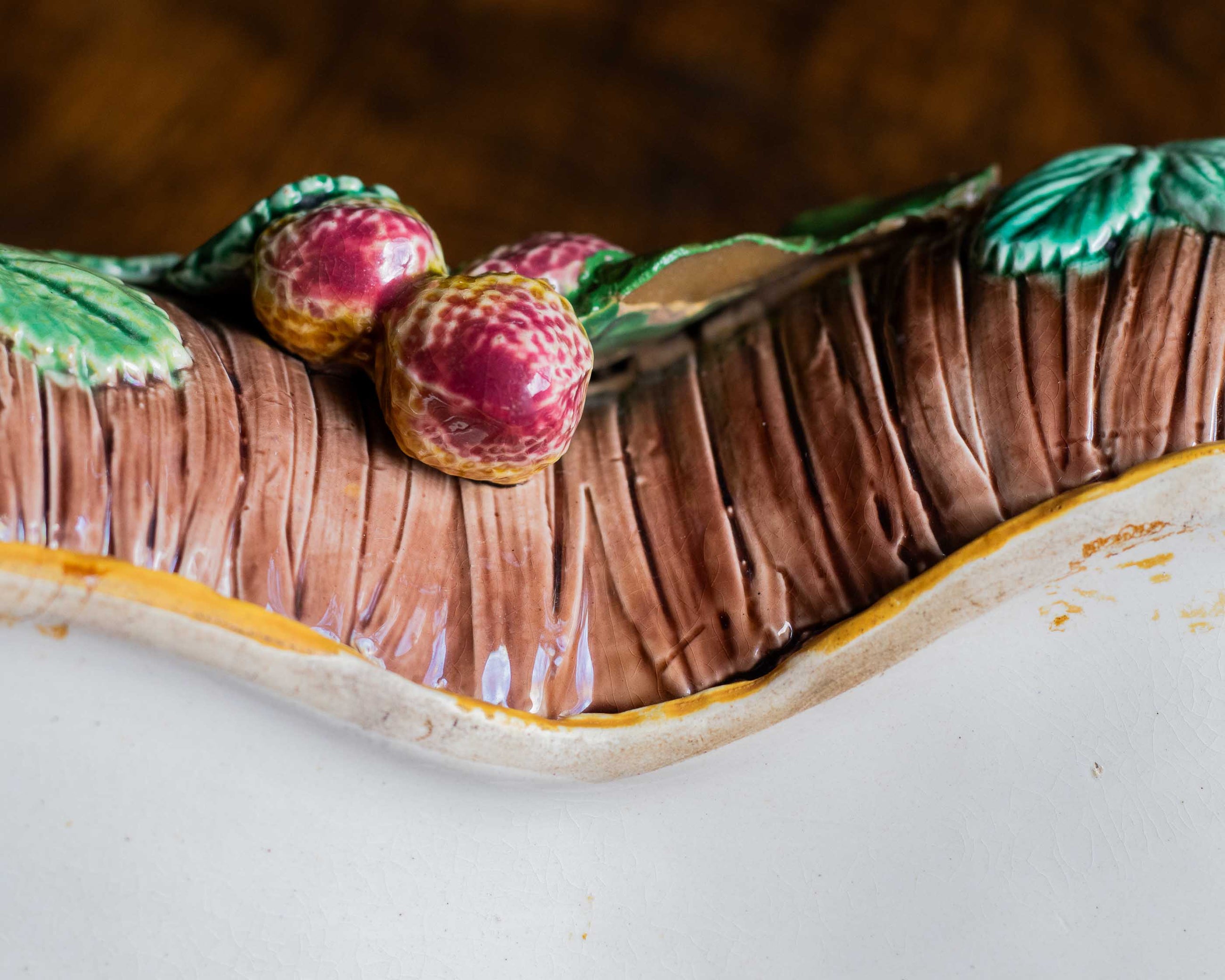 Close-up of a ceramic dish resembling with fruit and leaves on top.