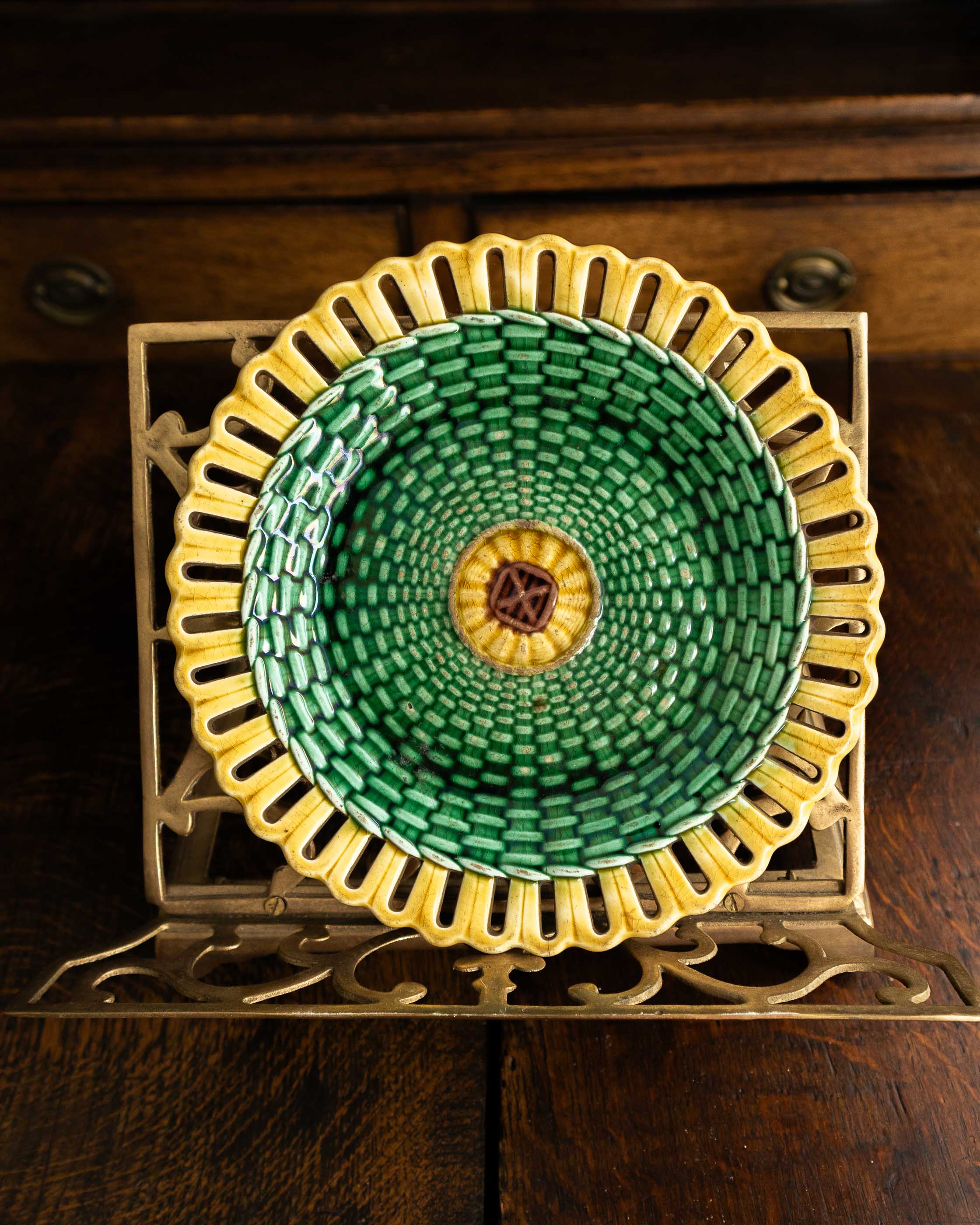 Decorative woven plate with green and yellow pattern on a wooden surface