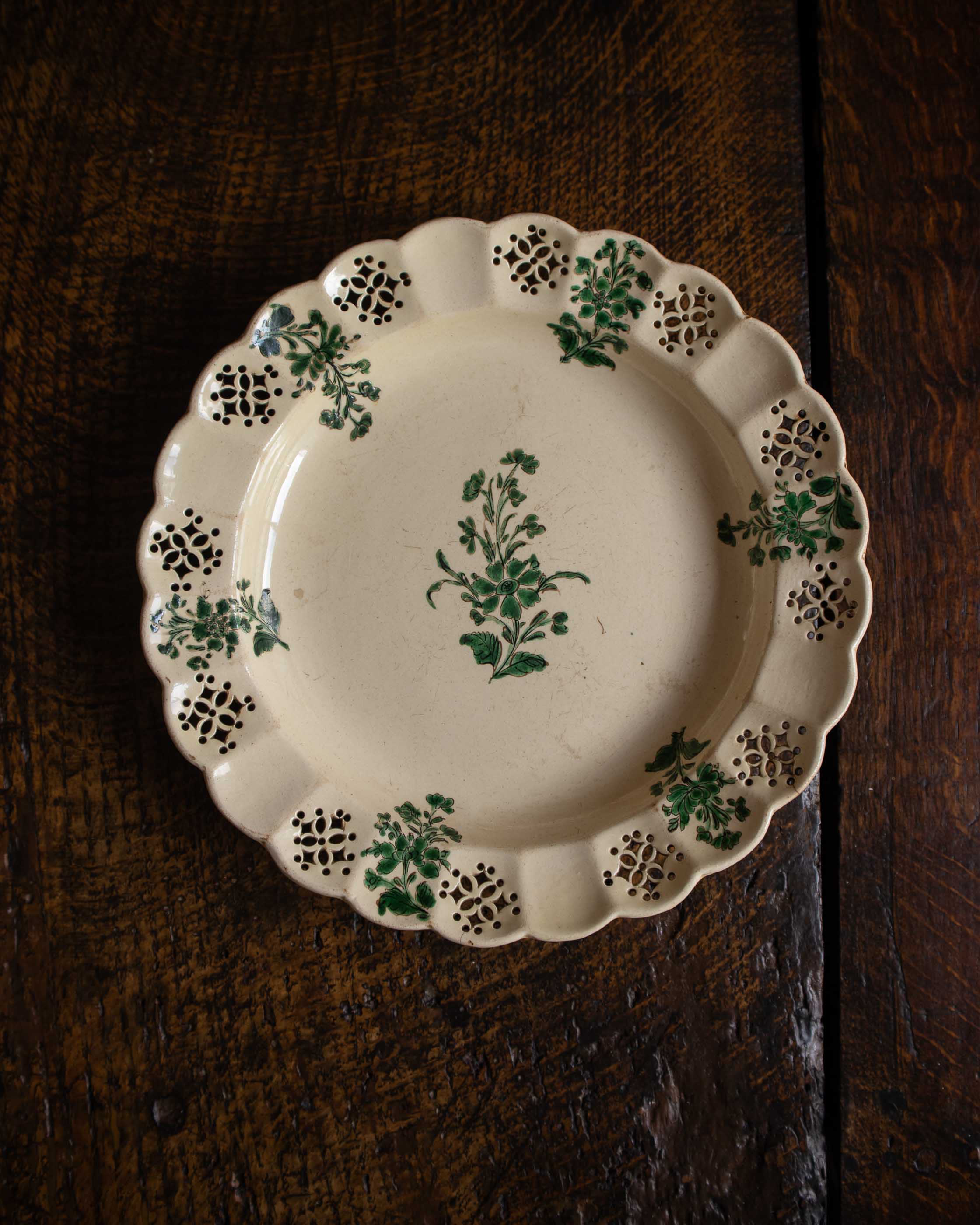 Decorative plate with green floral patterns on a wooden surface