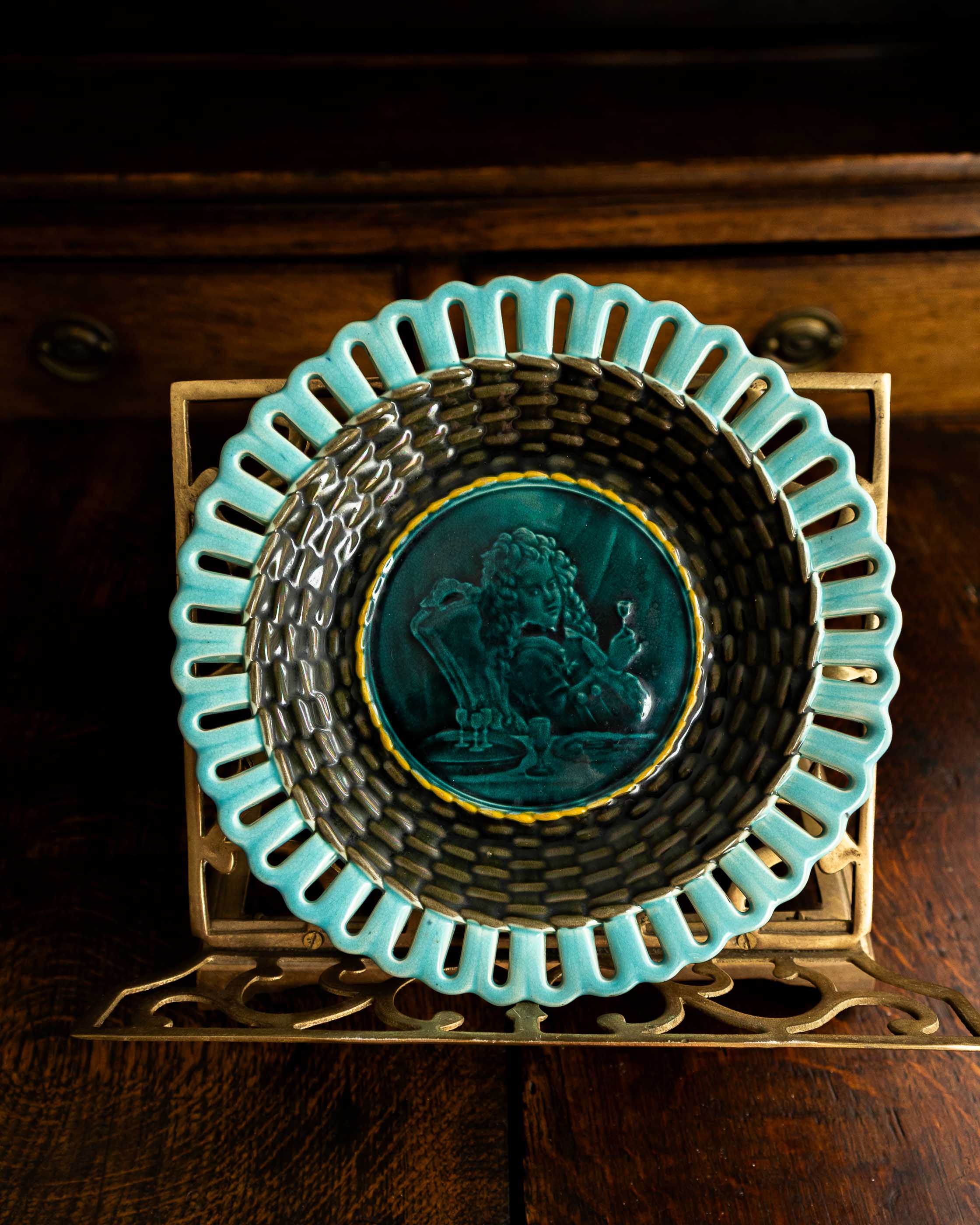 Decorative plate with teal rim and central design on a wooden stand