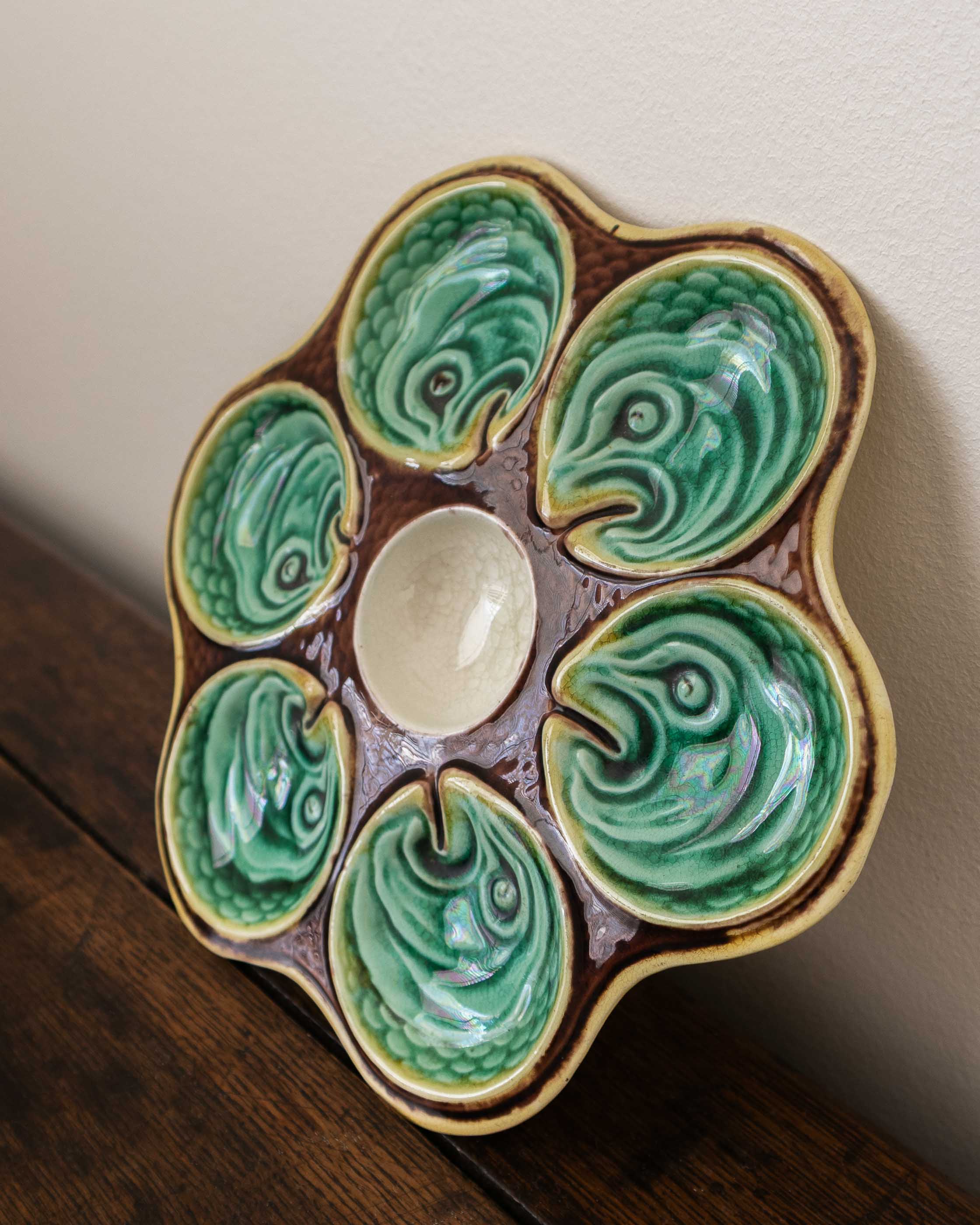 Ceramic oyster plate with green shell design on a wooden surface