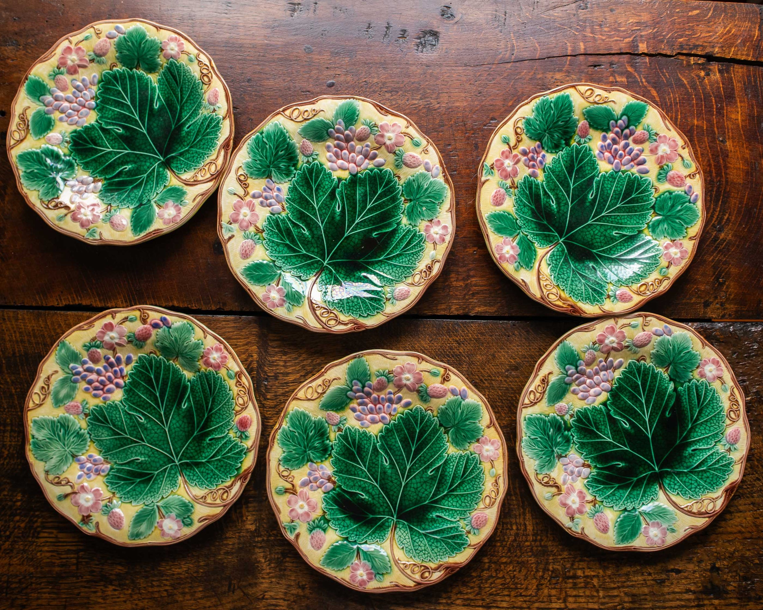 Set of six ceramic plates with leaf designs on a wooden surface