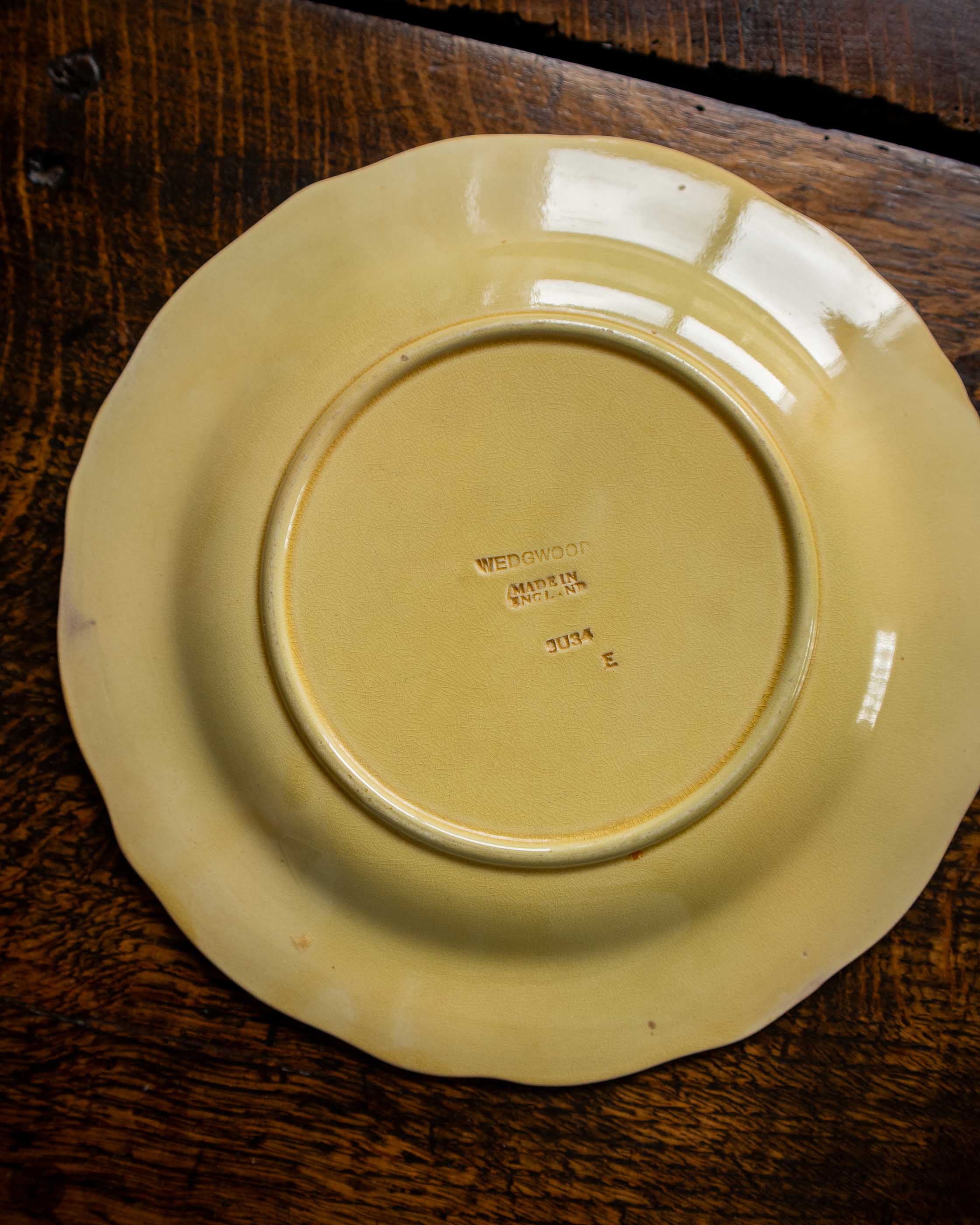 Yellow ceramic plate with 'Wedgwood' branding on a wooden surface