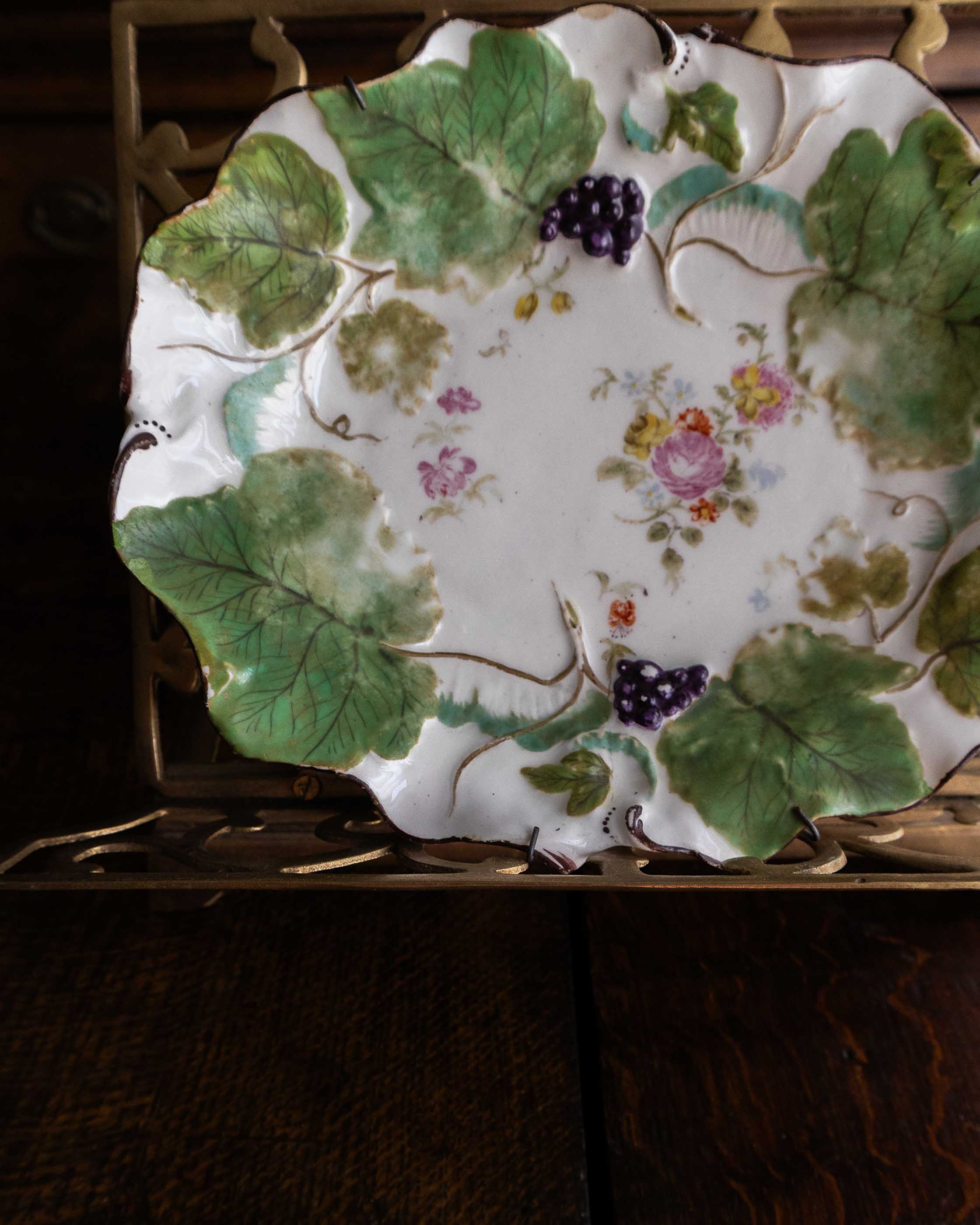 Decorative ceramic plate with floral and leaf patterns on a wooden surface