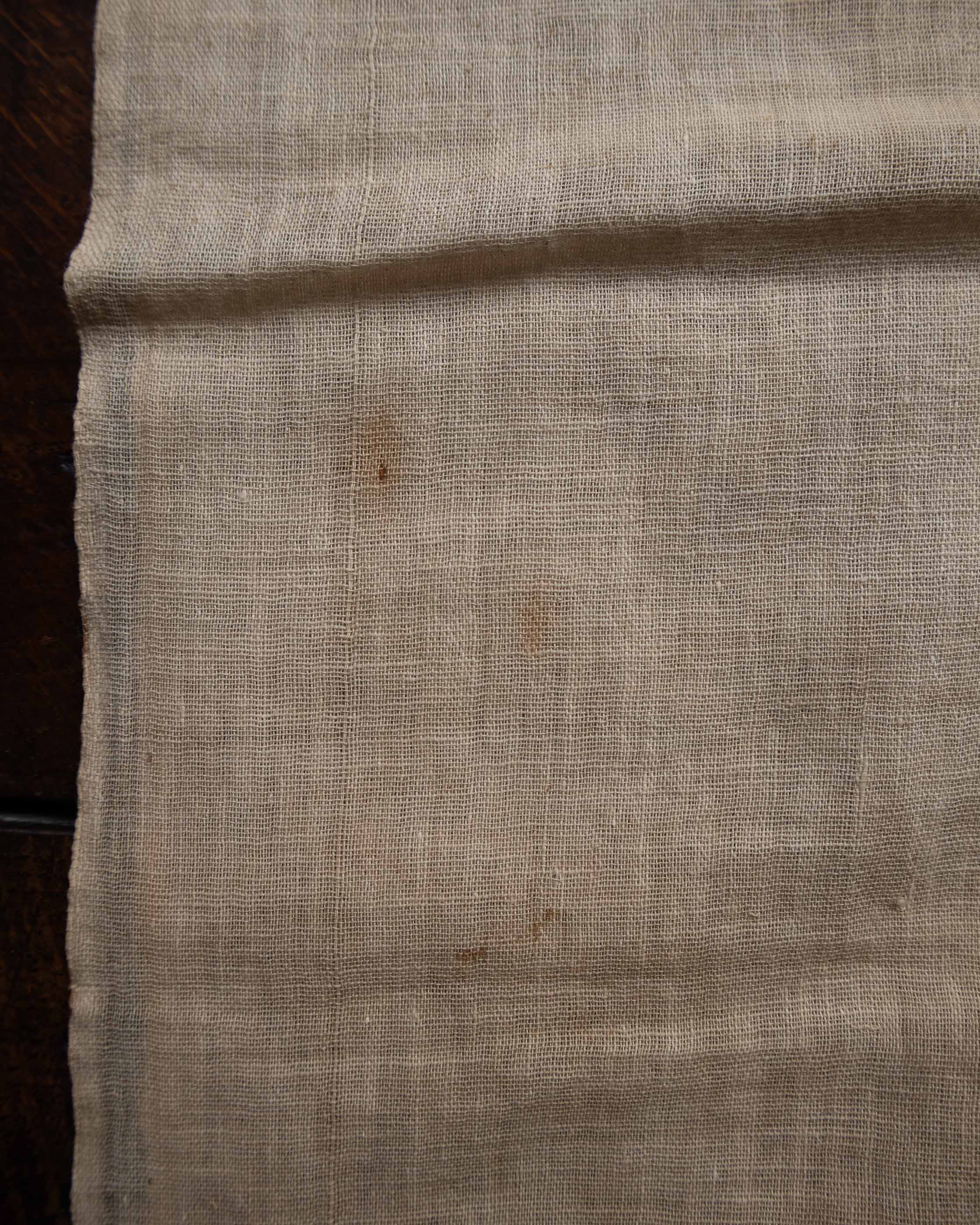 Close-up of beige fabric with a dark stain on a wooden surface
