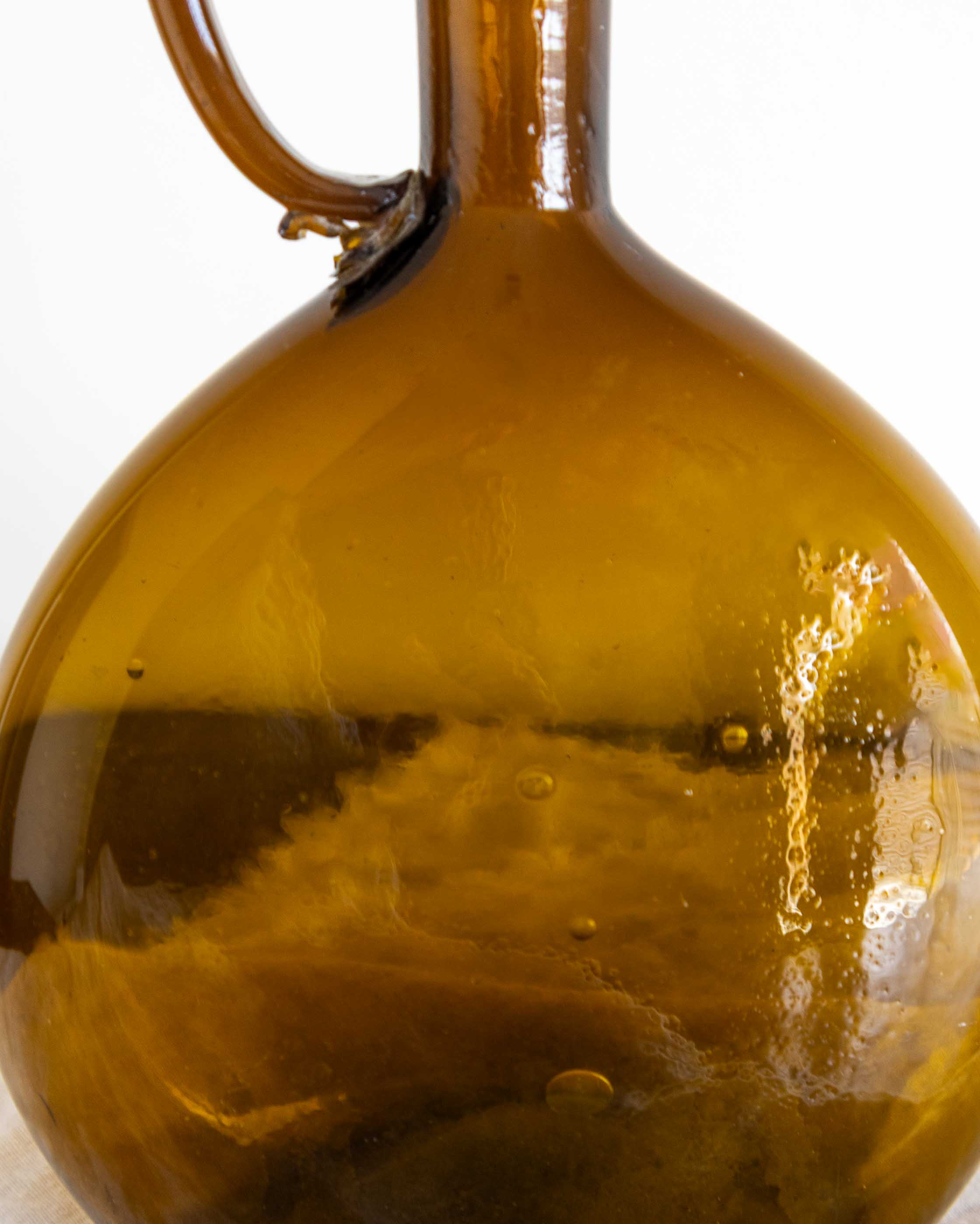 Close-up of a brown glass bottle with a handle on a white background