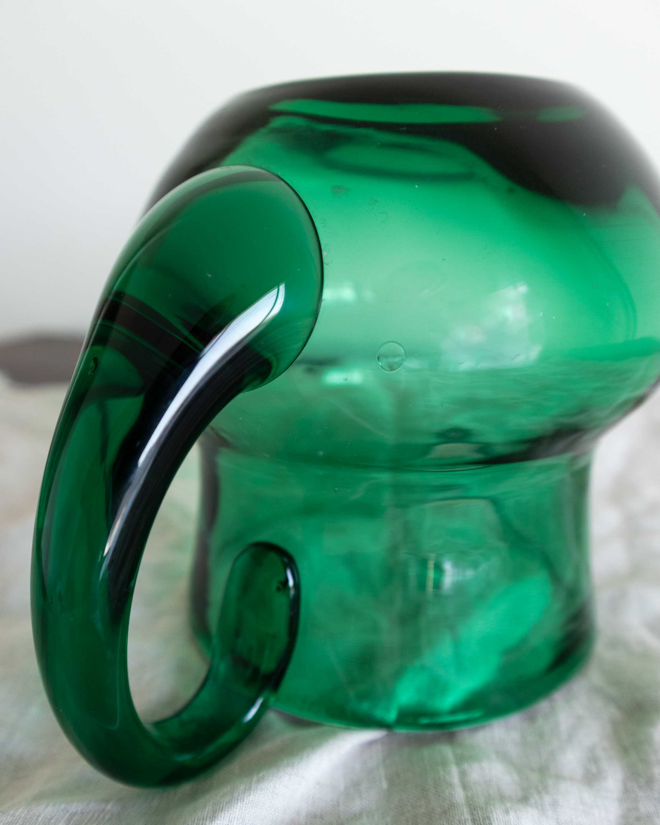 Green glass jug with a handle on a white background