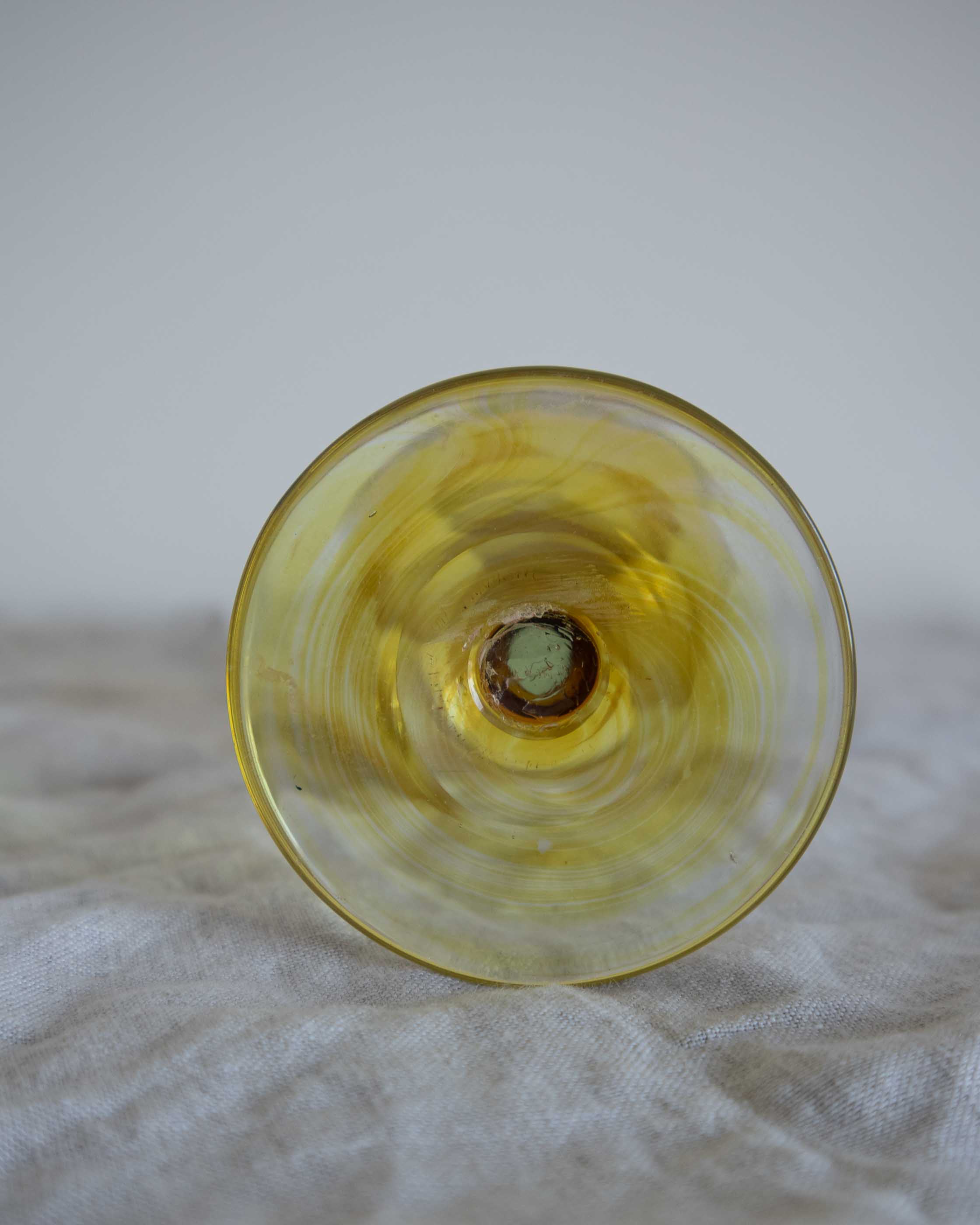 Yellow glass object on a textured surface with a neutral background