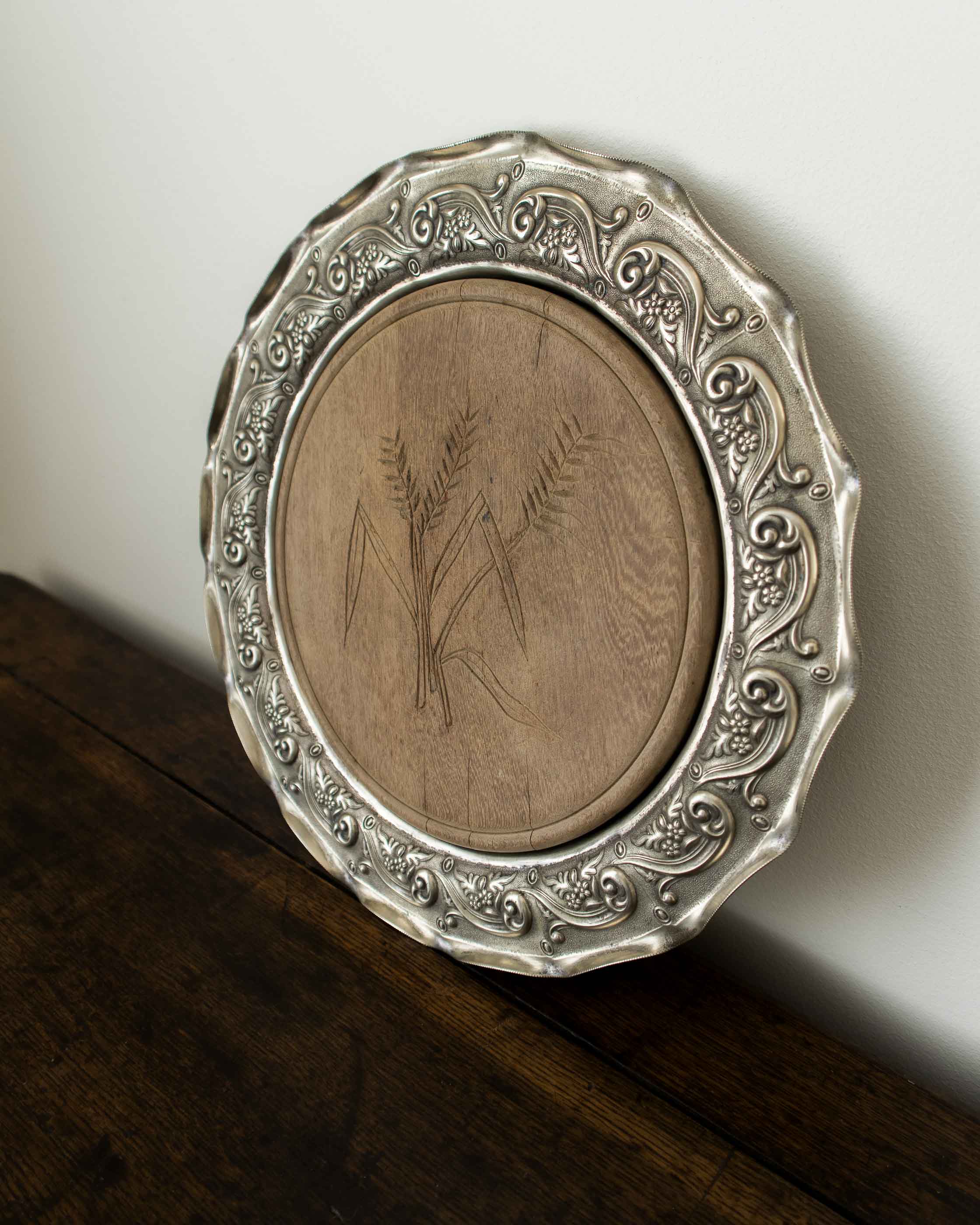 Decorative silver plate with a wooden center on a wooden surface