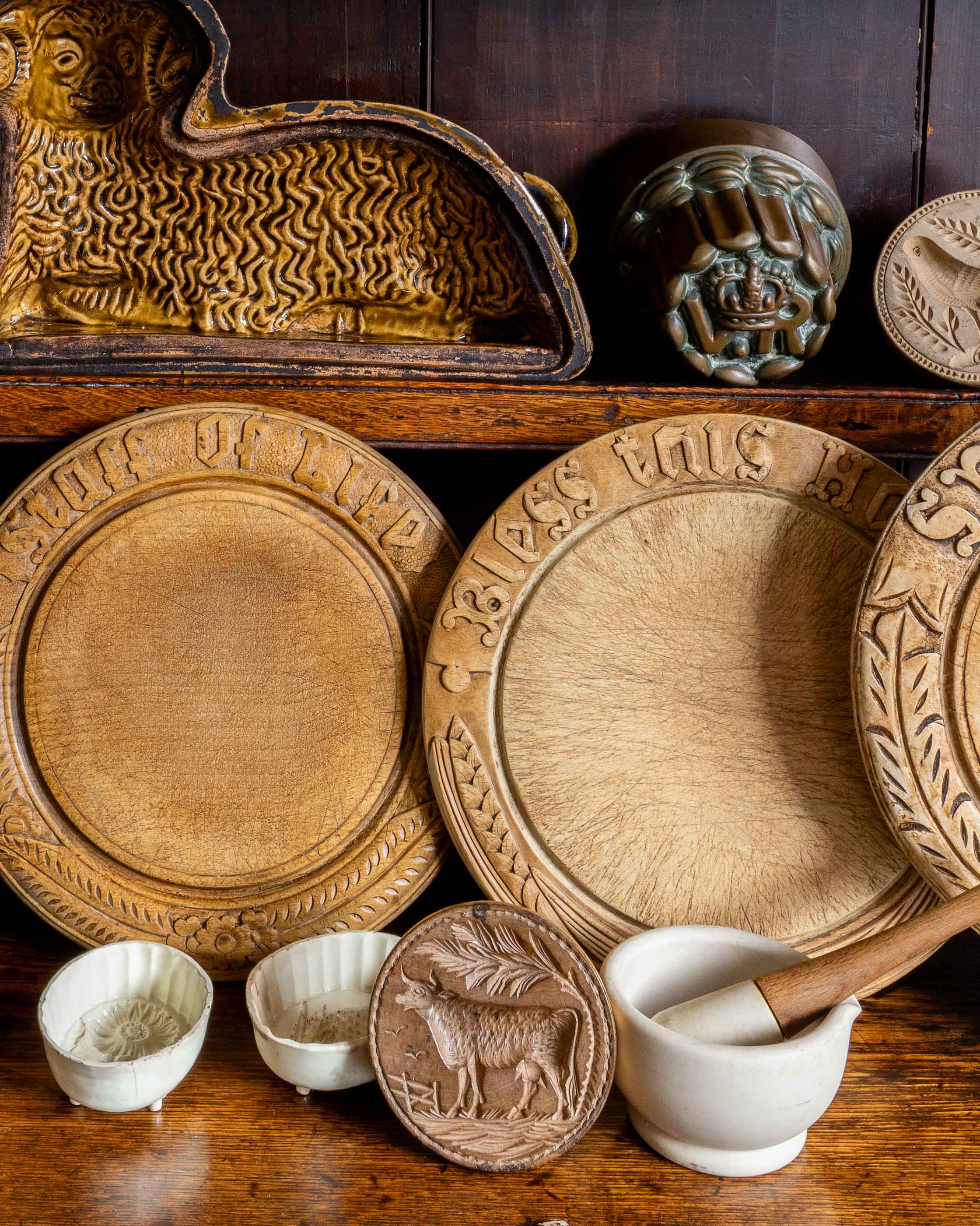 Collection of wooden breadboards and decorative moulds on a wooden shelf