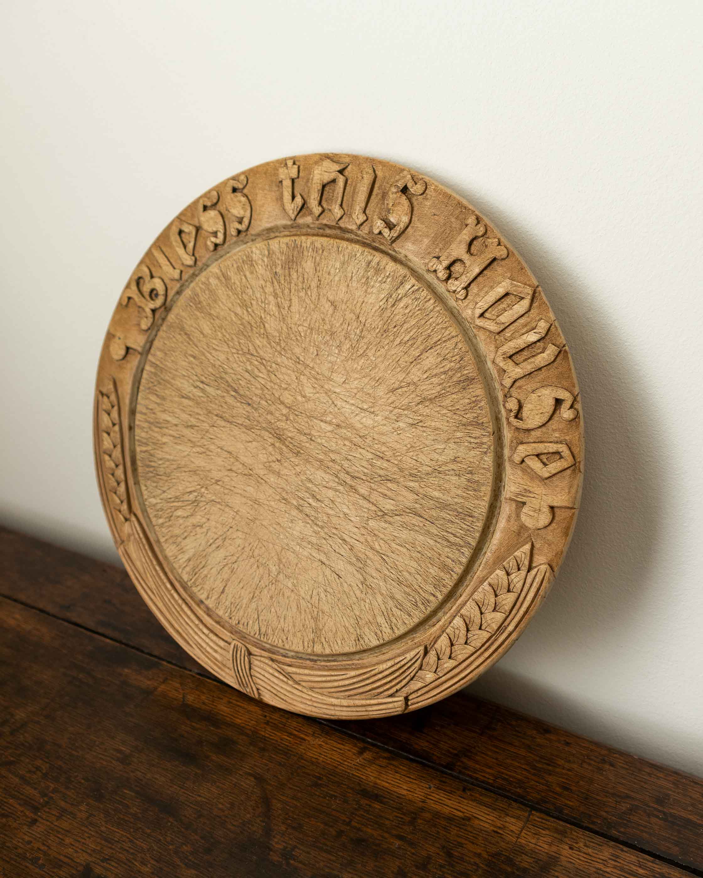 Wooden breadboard with carved text on a wooden surface