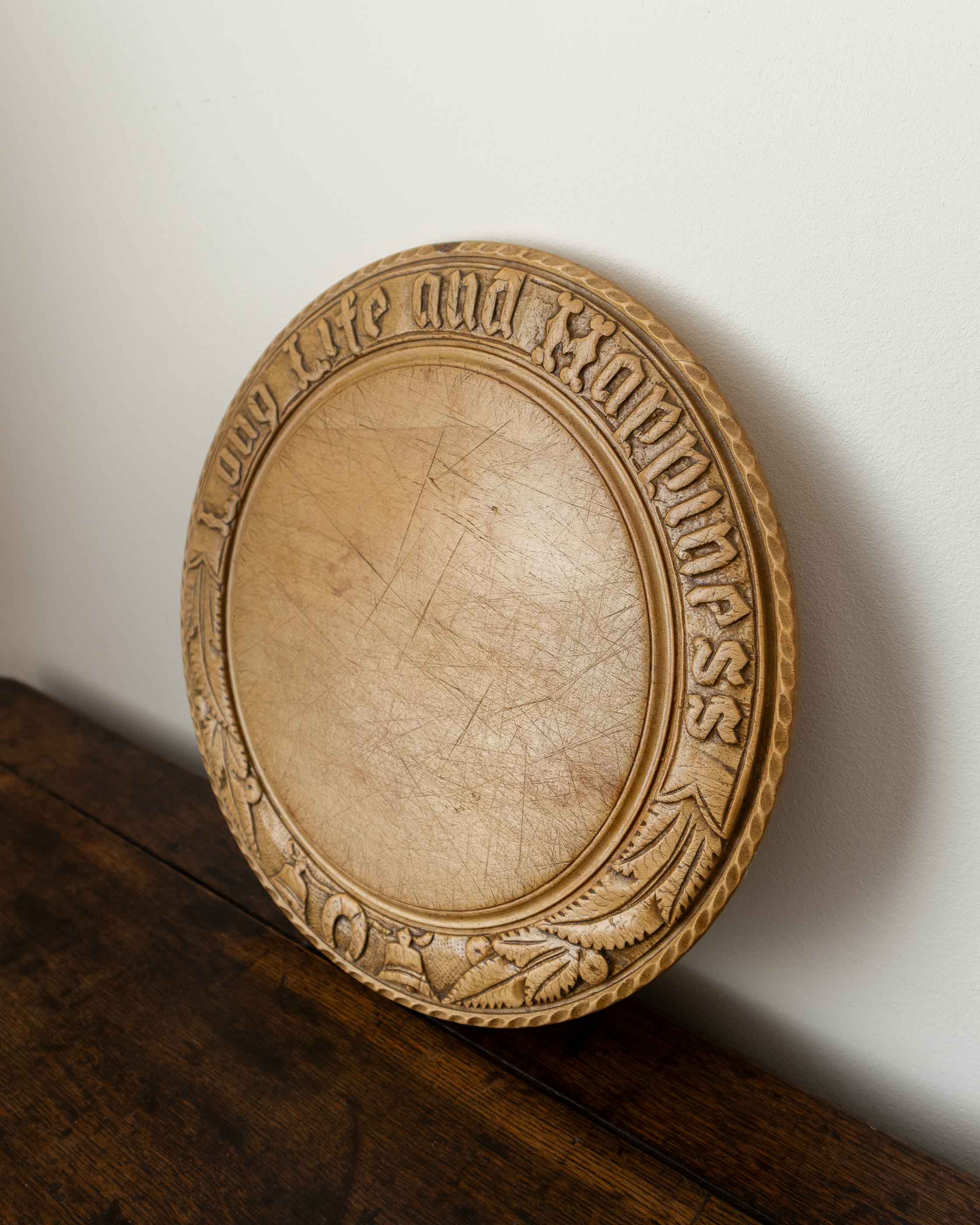 Wooden breadboard with carved text on a wooden surface
