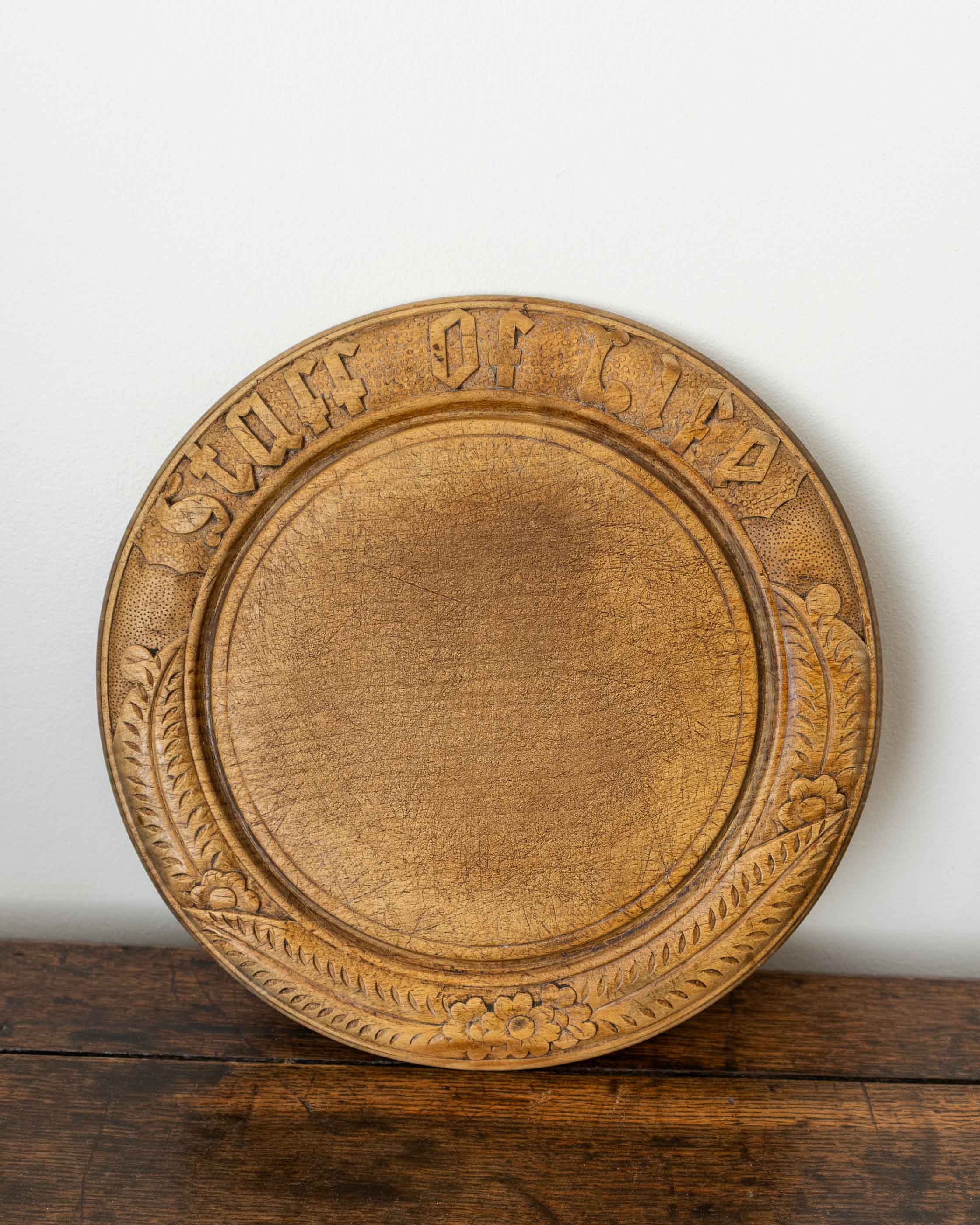 Wooden breadboard with carved text on a wooden surface