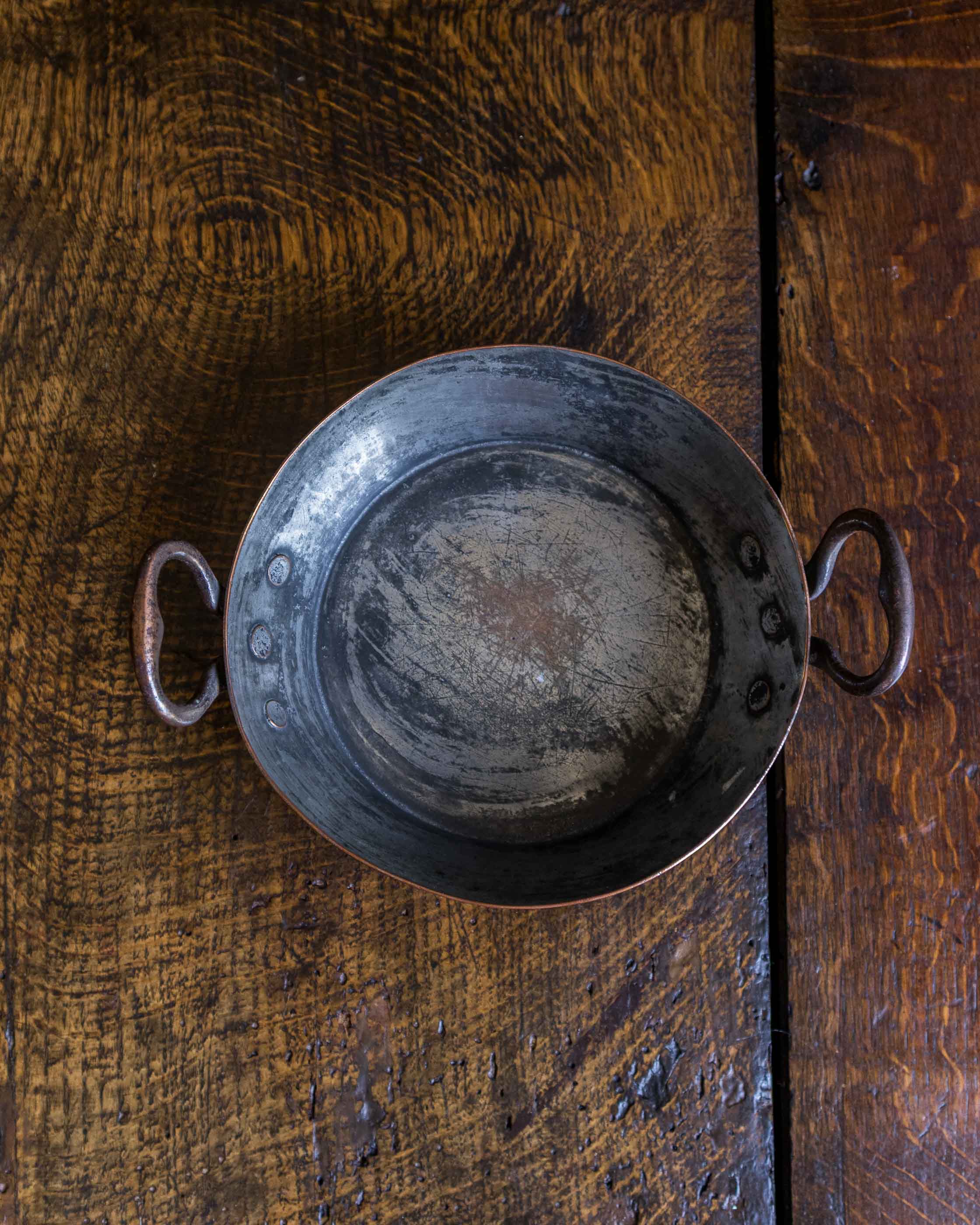 Vintage copper dish with handles on a wooden surface