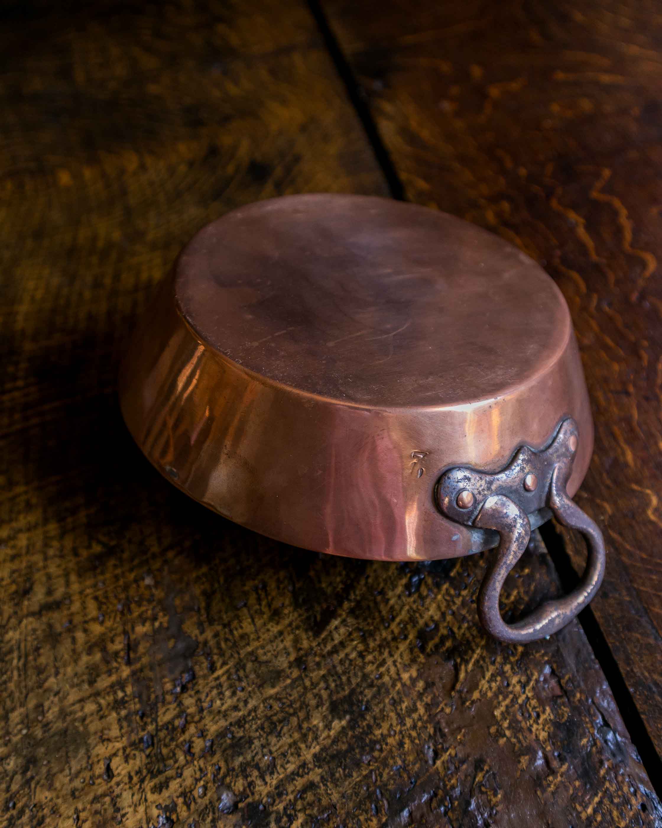 Copper dish with a handle on a wooden surface