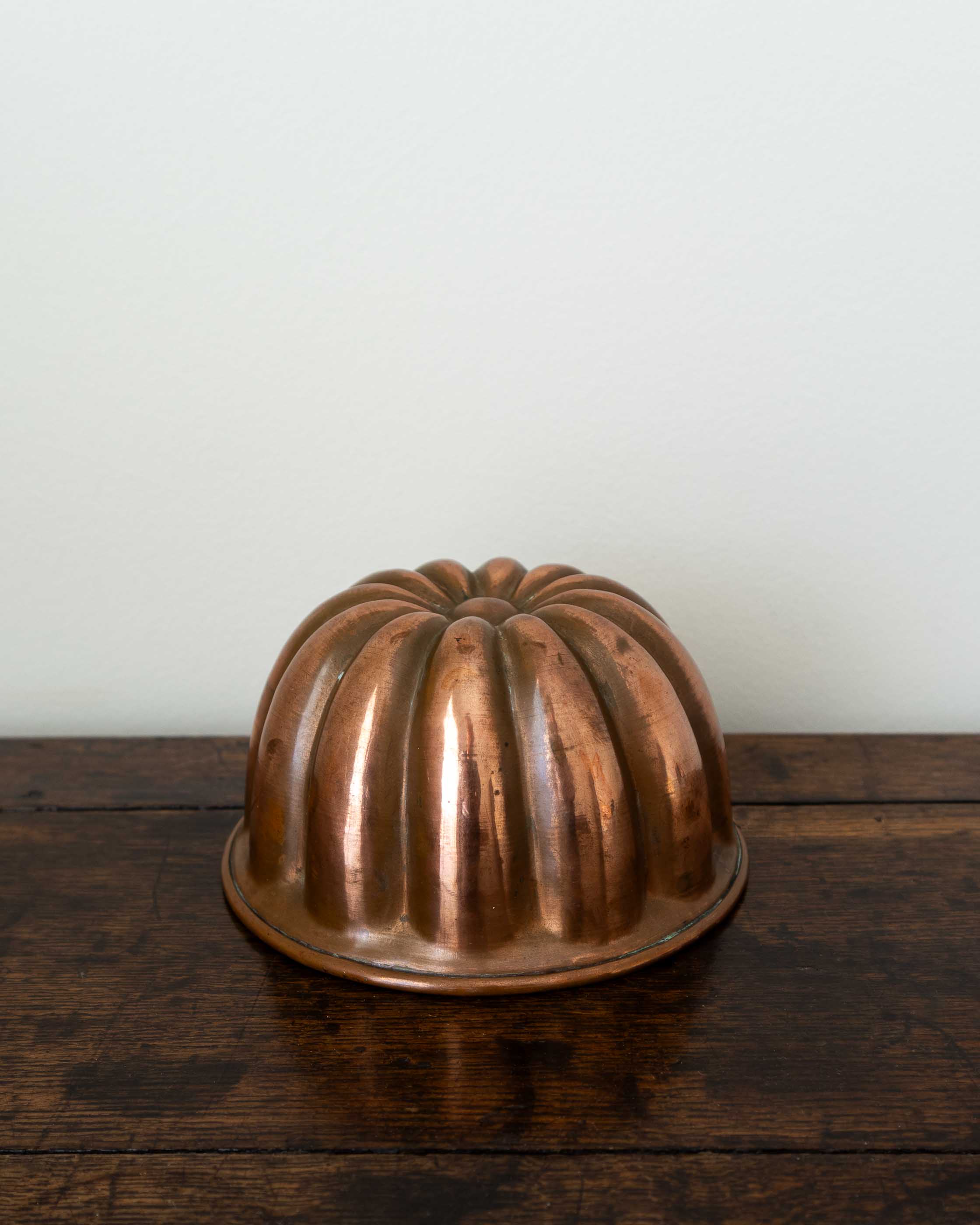 Copper jelly mould on a wooden surface with a white background