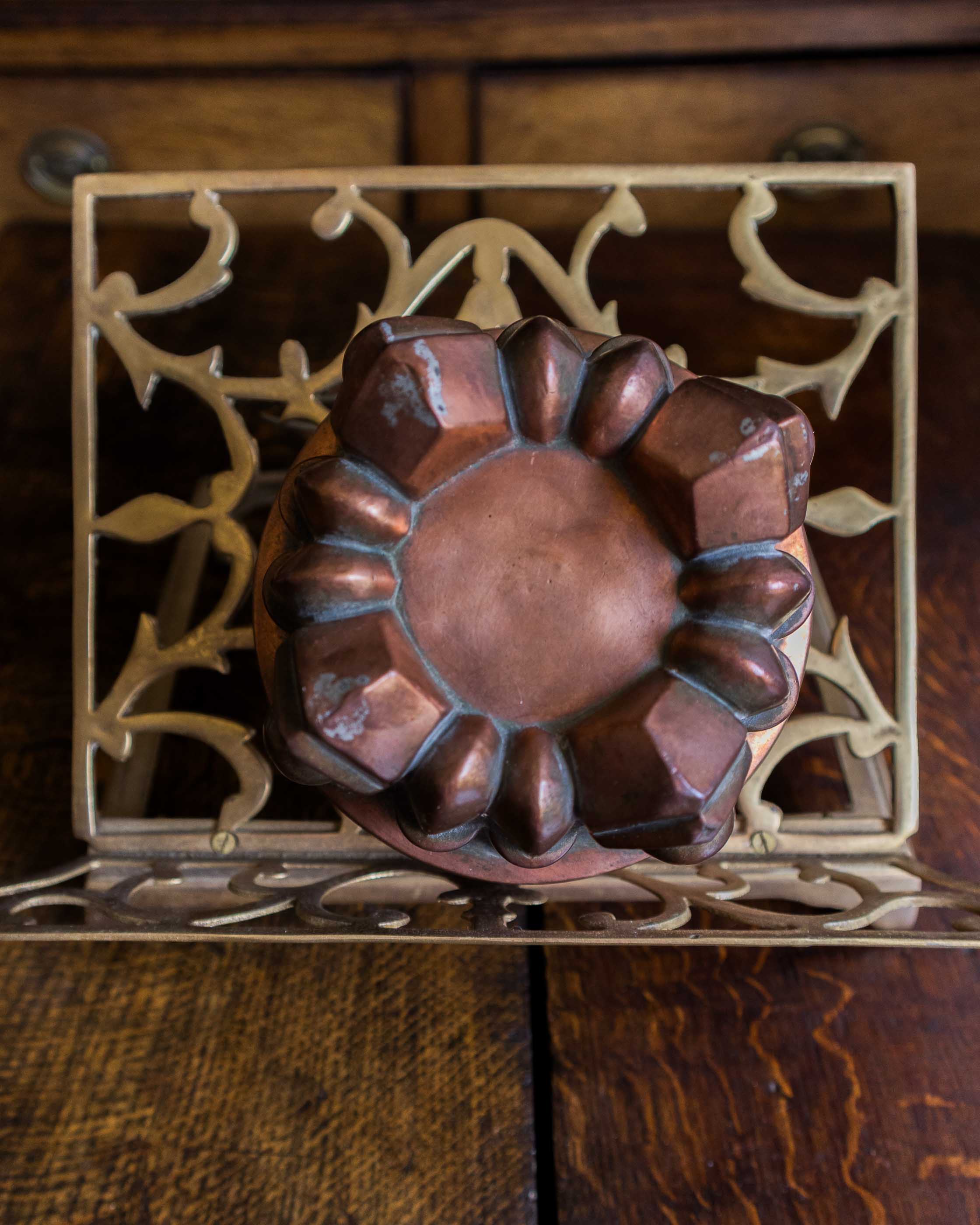 Decorative metal trivet with a copper-jelly mould on a wooden surface