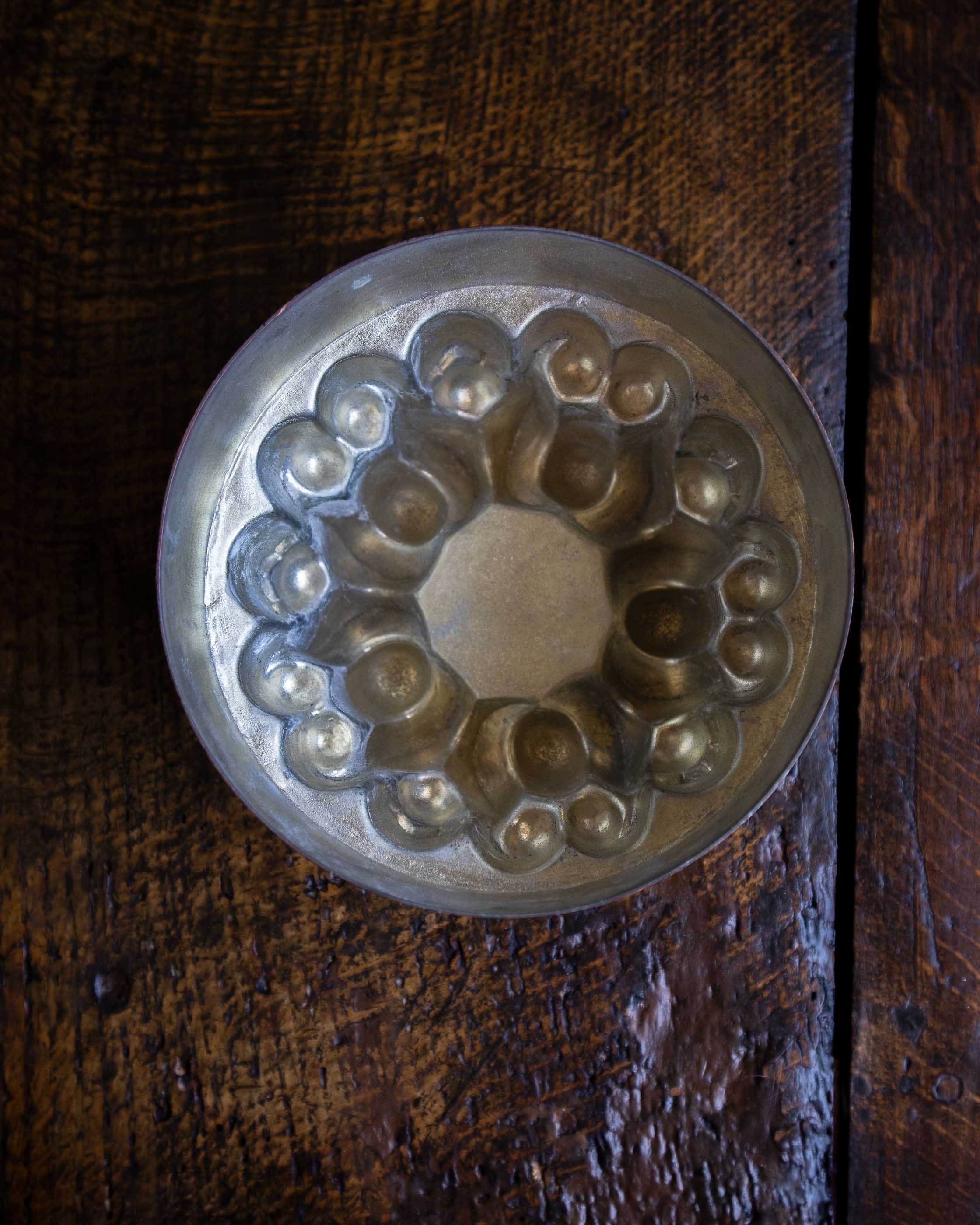 Decorative copper jelly mould with intricate design on a wooden surface