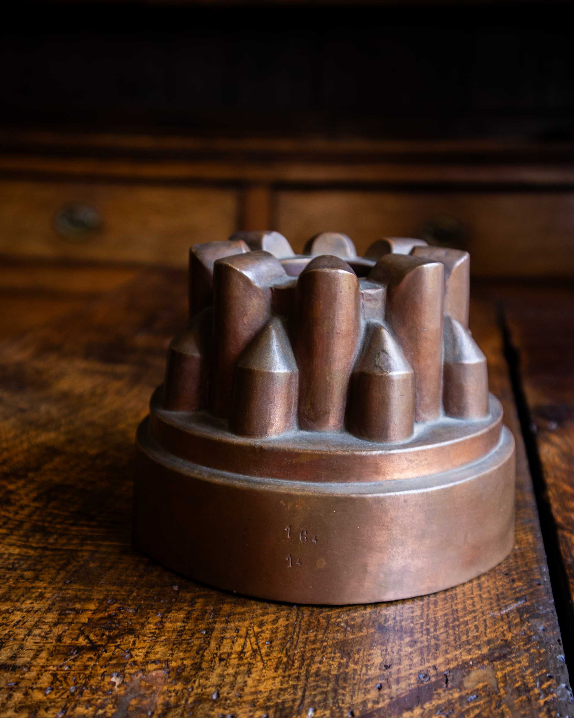 Copper jelly mould with pointed shapes on a wooden surface