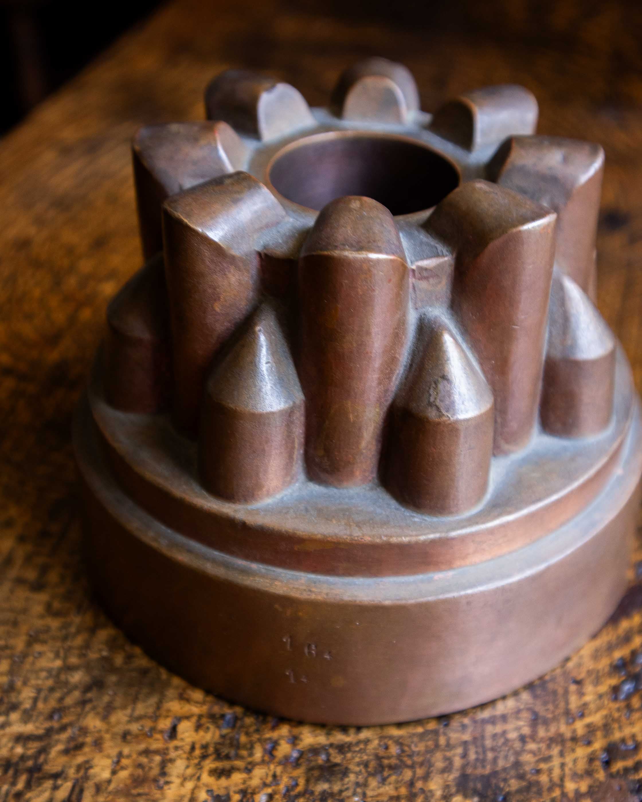 Copper jelly mould with pointed shapes on a wooden surface