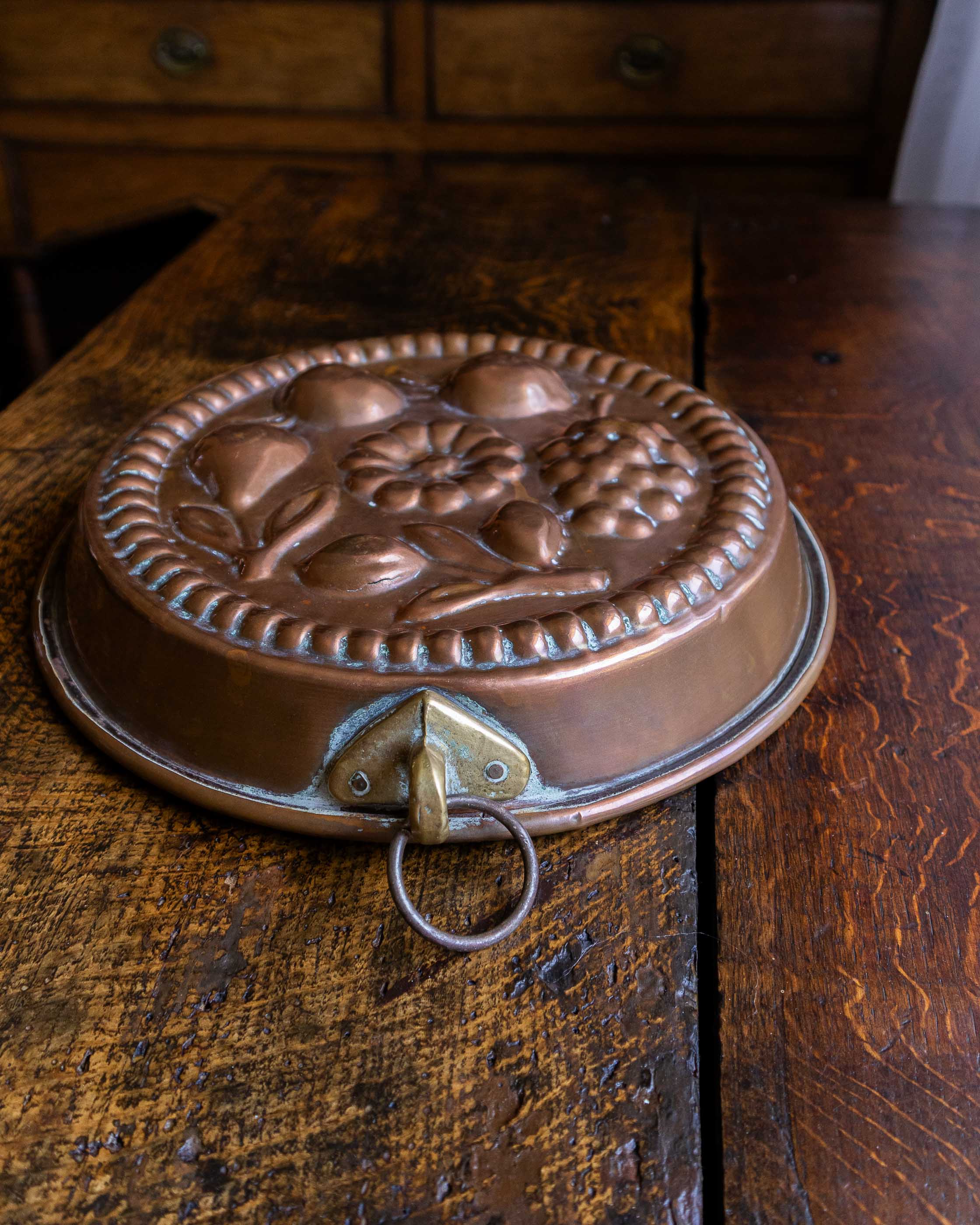 Copper mould with floral design on a wooden surface