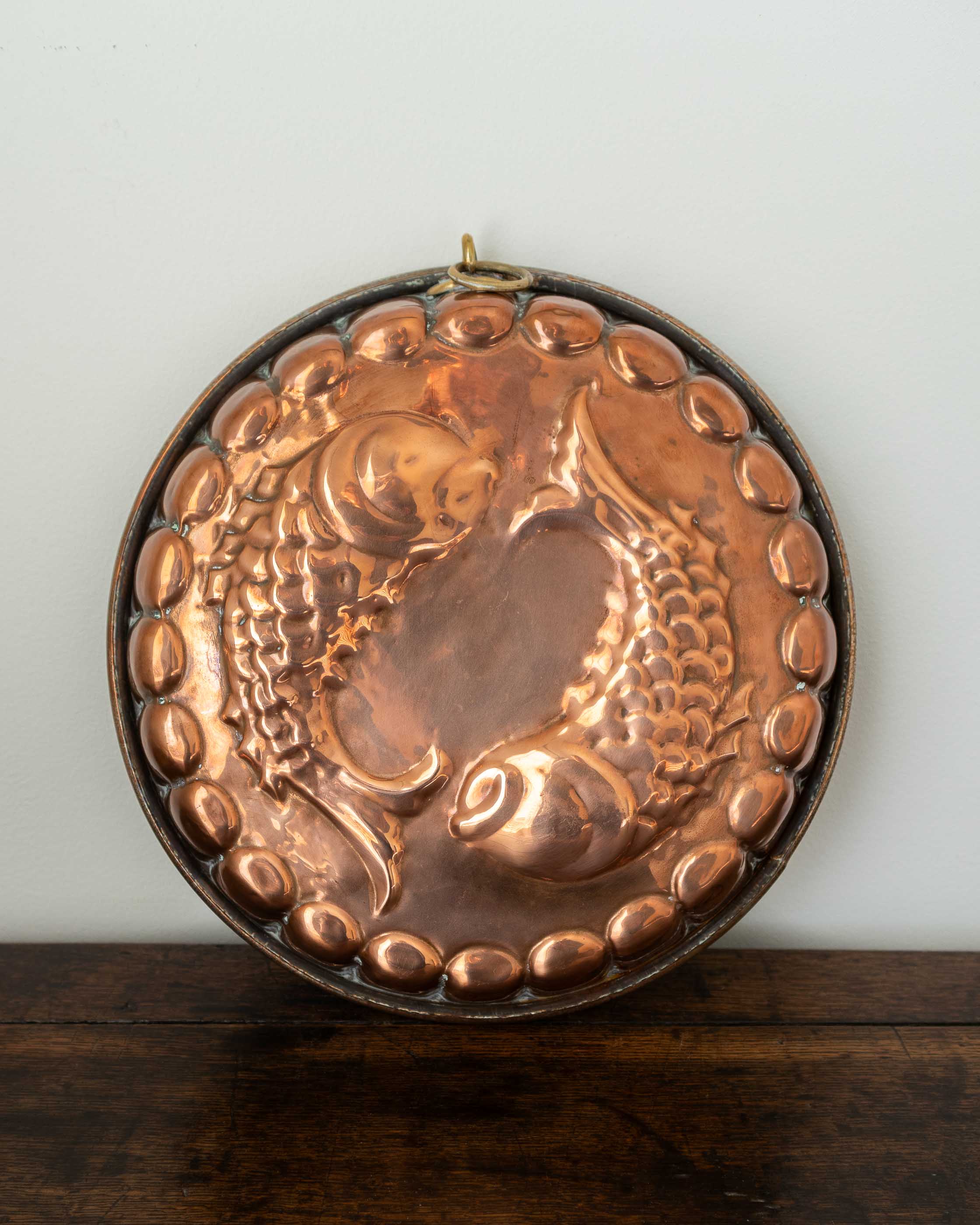 Copper mould with a fish design on a wooden surface and light white background