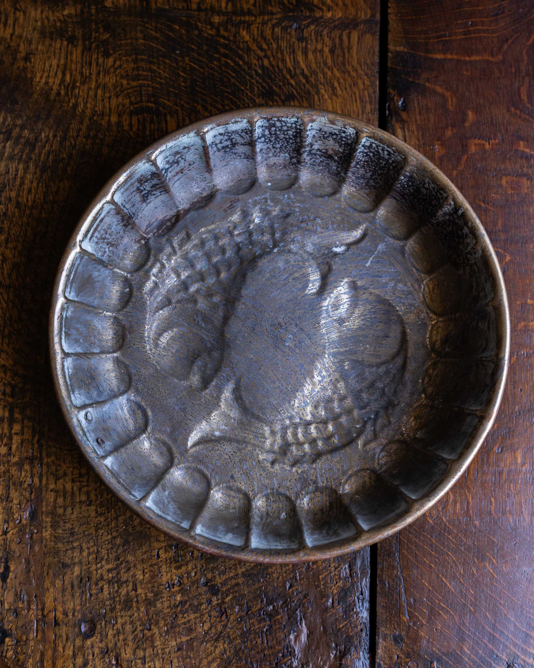 Decorative copper mould with fish design on a wooden surface