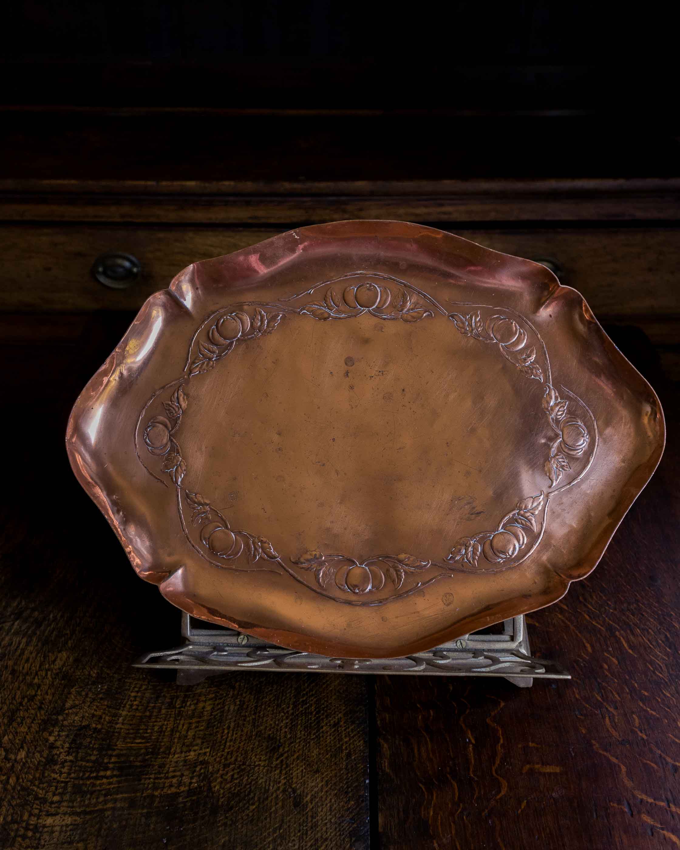 Decorative copper tray on a stand with a dark background
