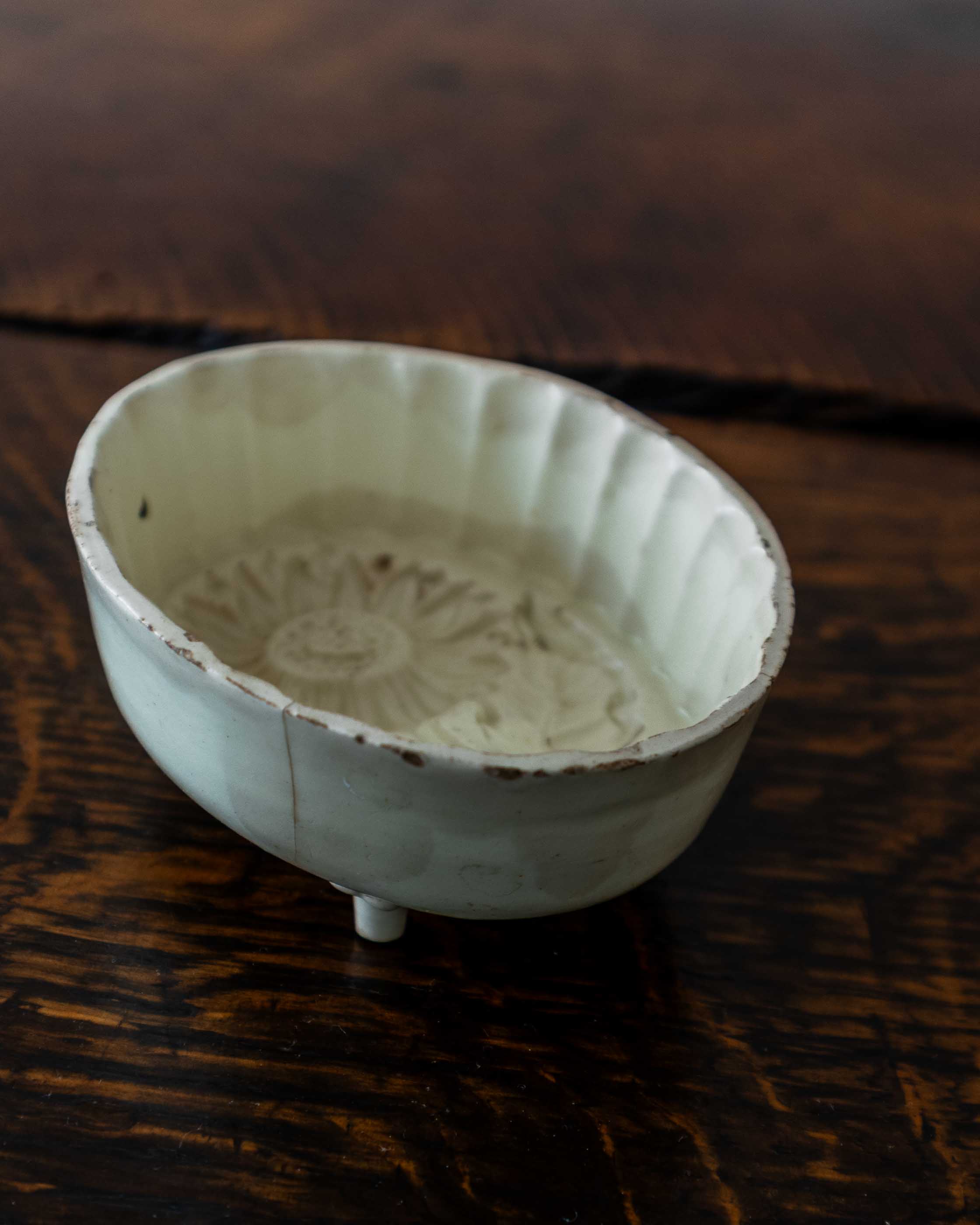 White ceramic mould with intricate patterns on a wooden surface