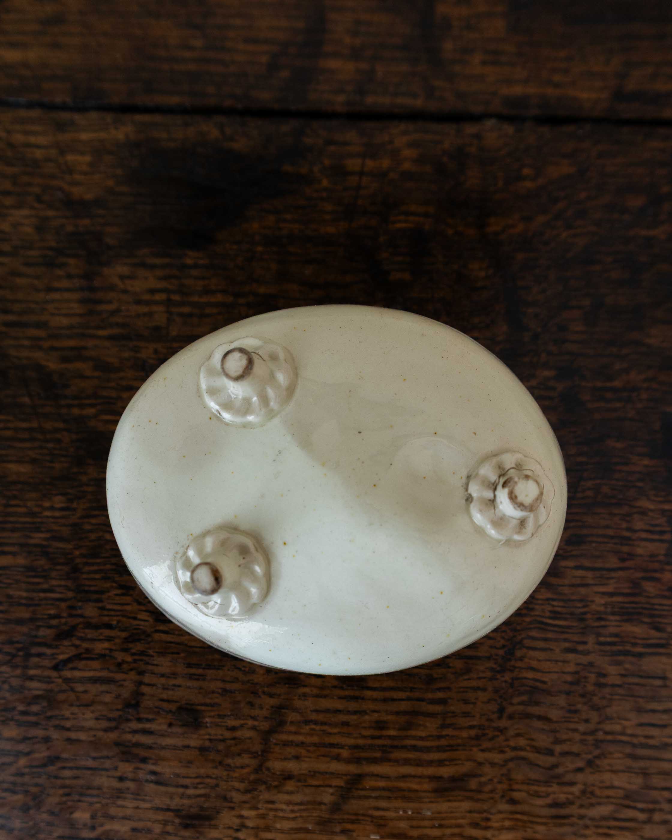 White ceramic mould with four small feet on a wooden surface