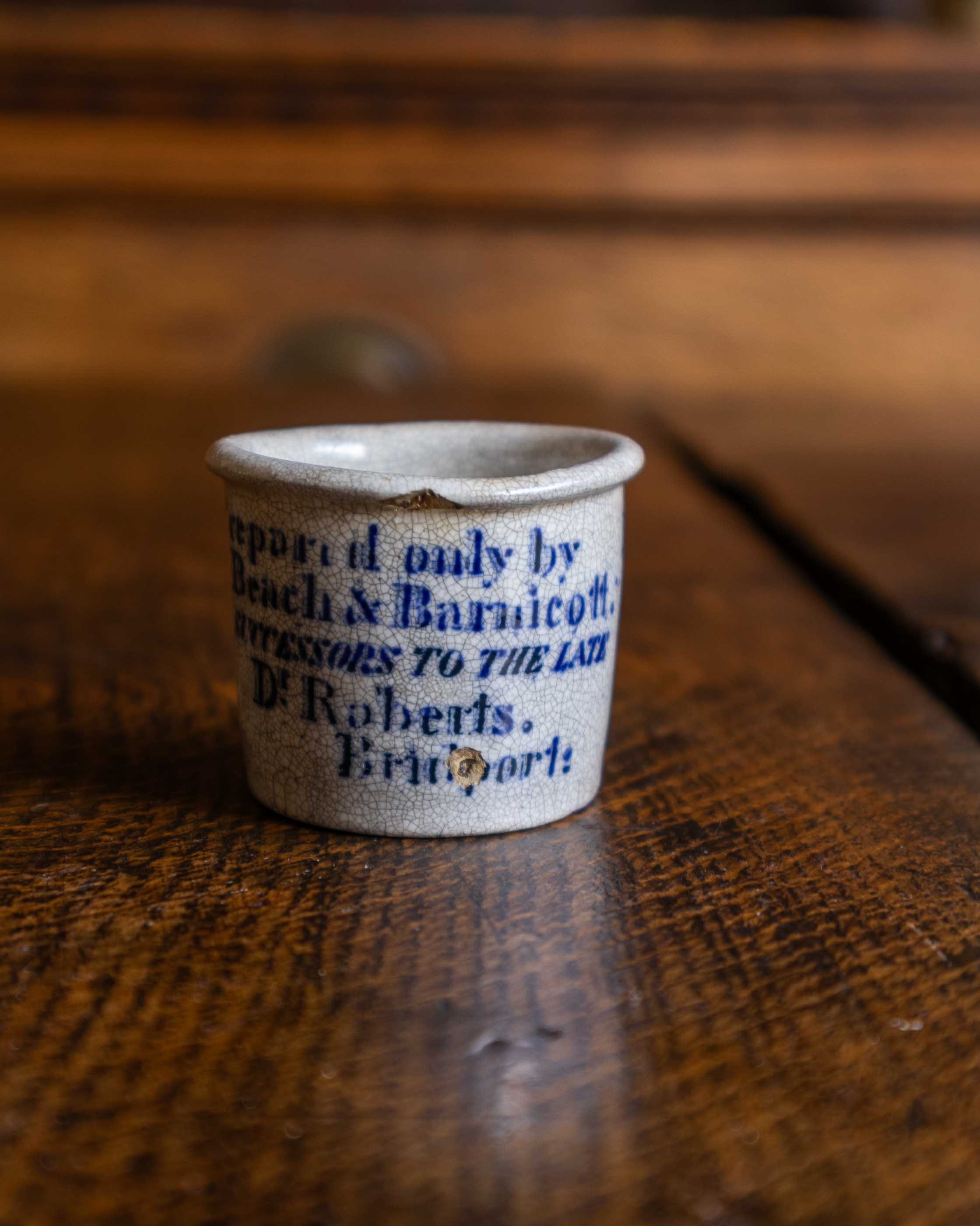 Small ceramic pot with text on a wooden surface