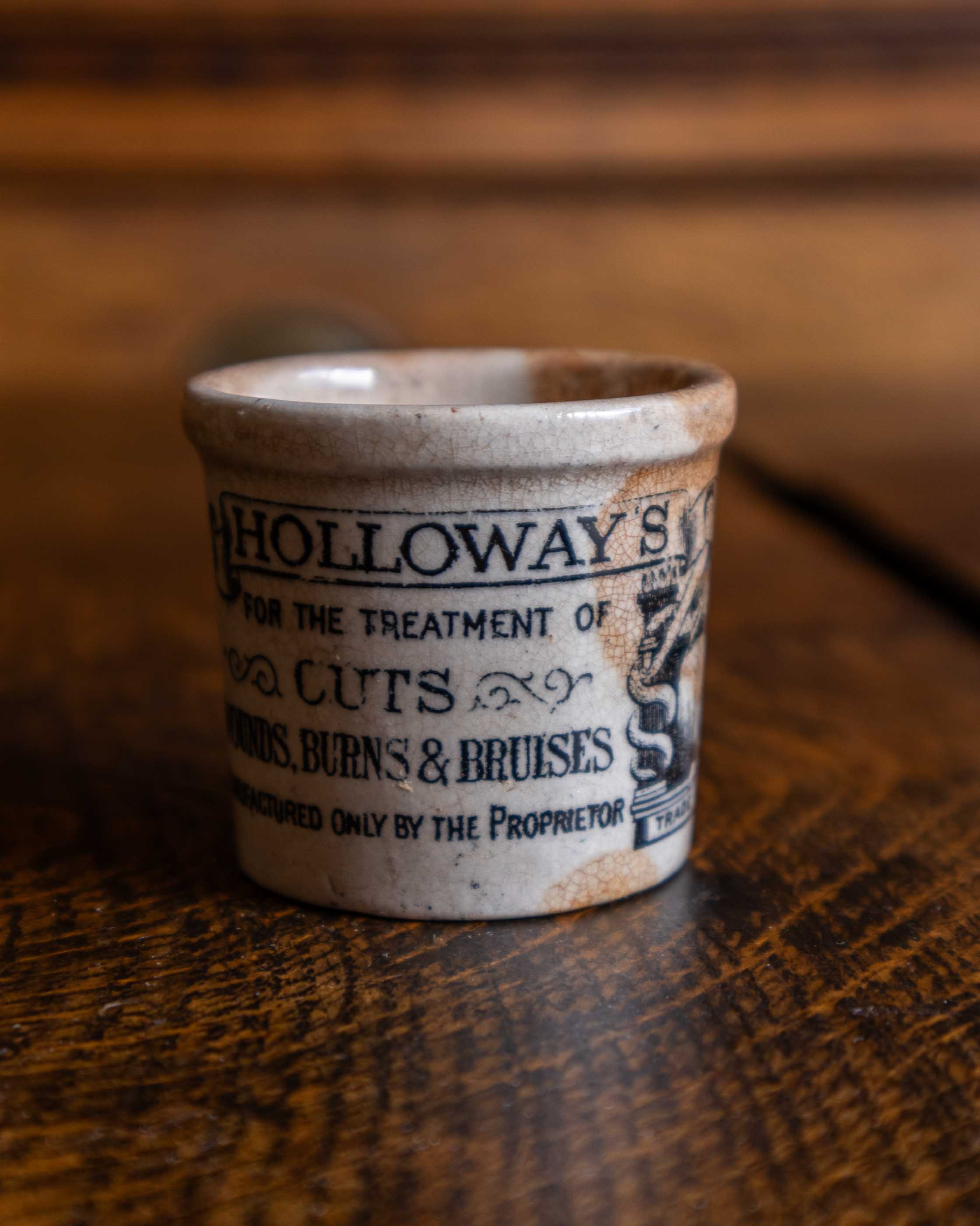 Vintage-style ceramic pot with text on a wooden surface