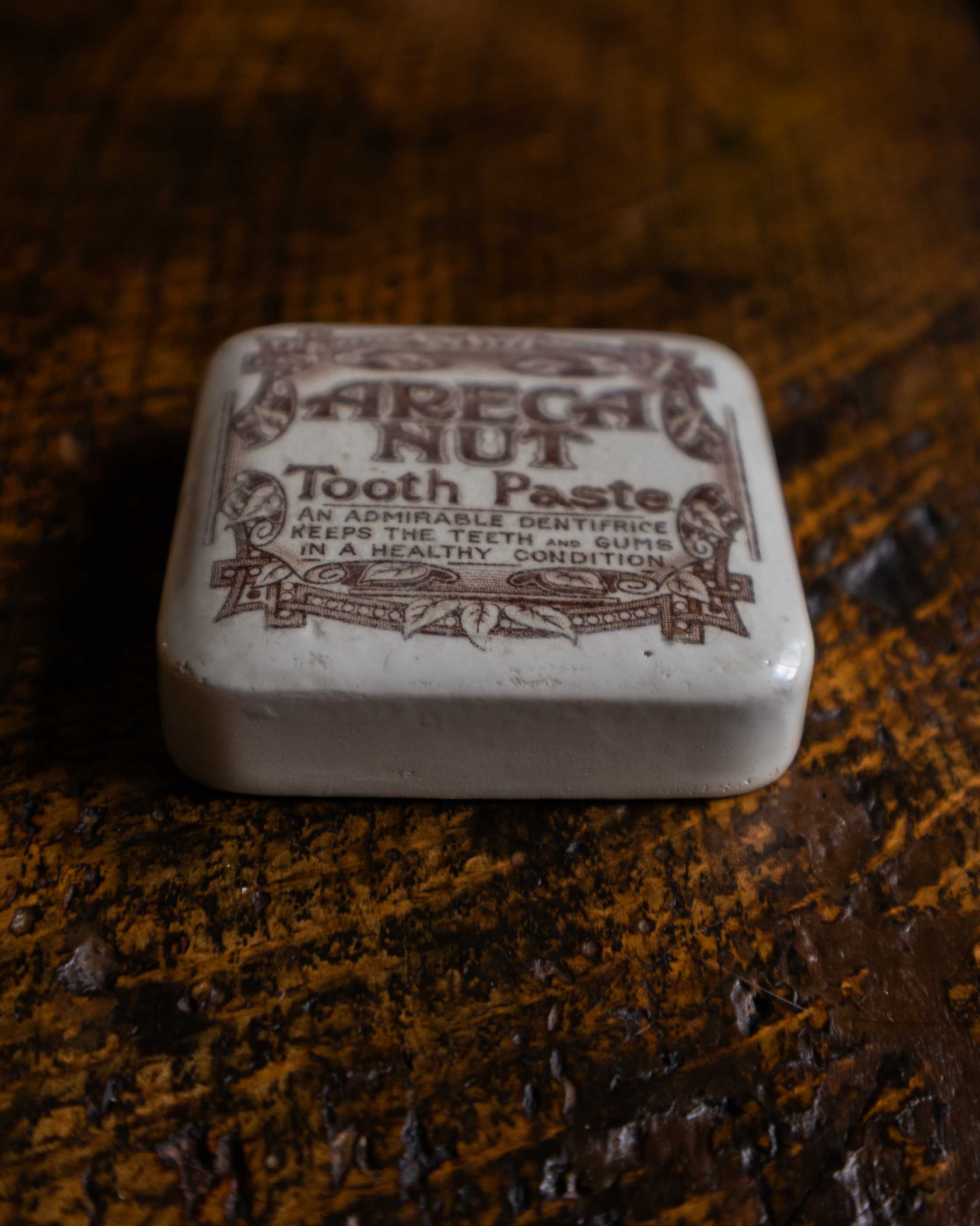 Areca Nut Tooth Paste lid on a wooden surface
