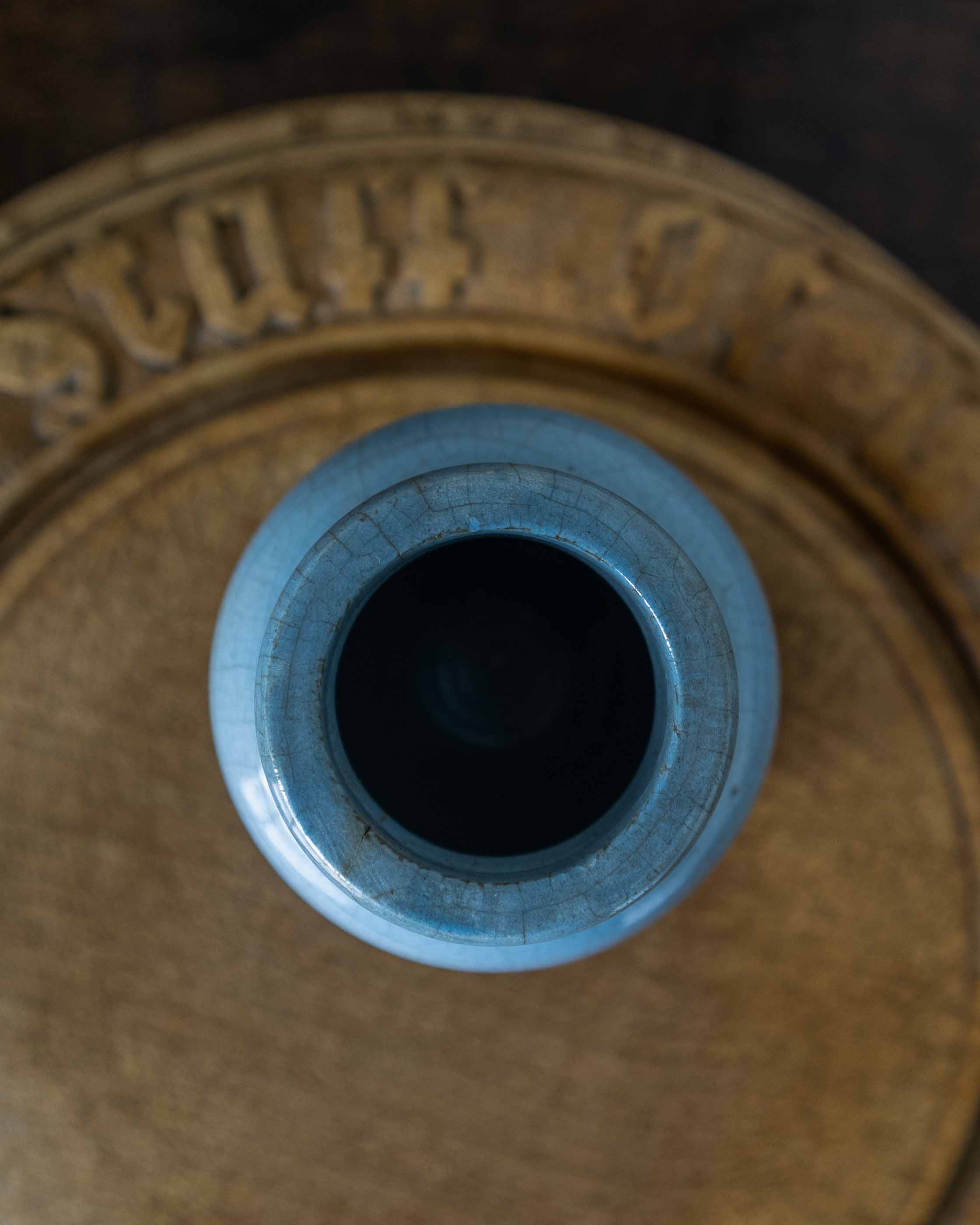 Close-up of a blue ceramic jar with a textured surface on a brown background