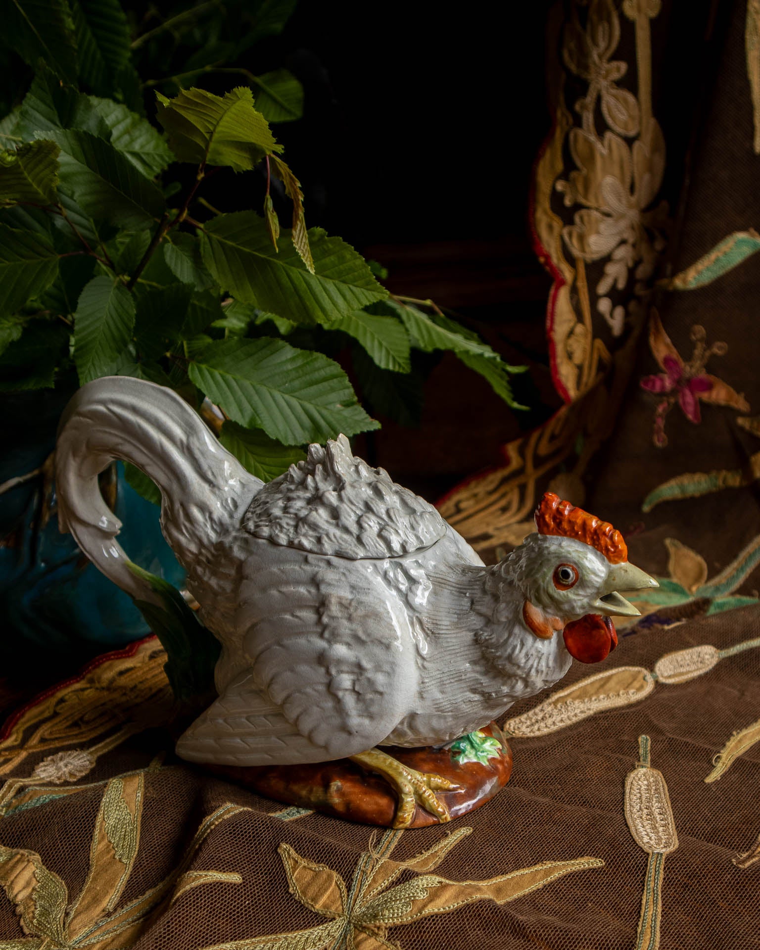 Decorative rooster teapot on a patterned fabric background
