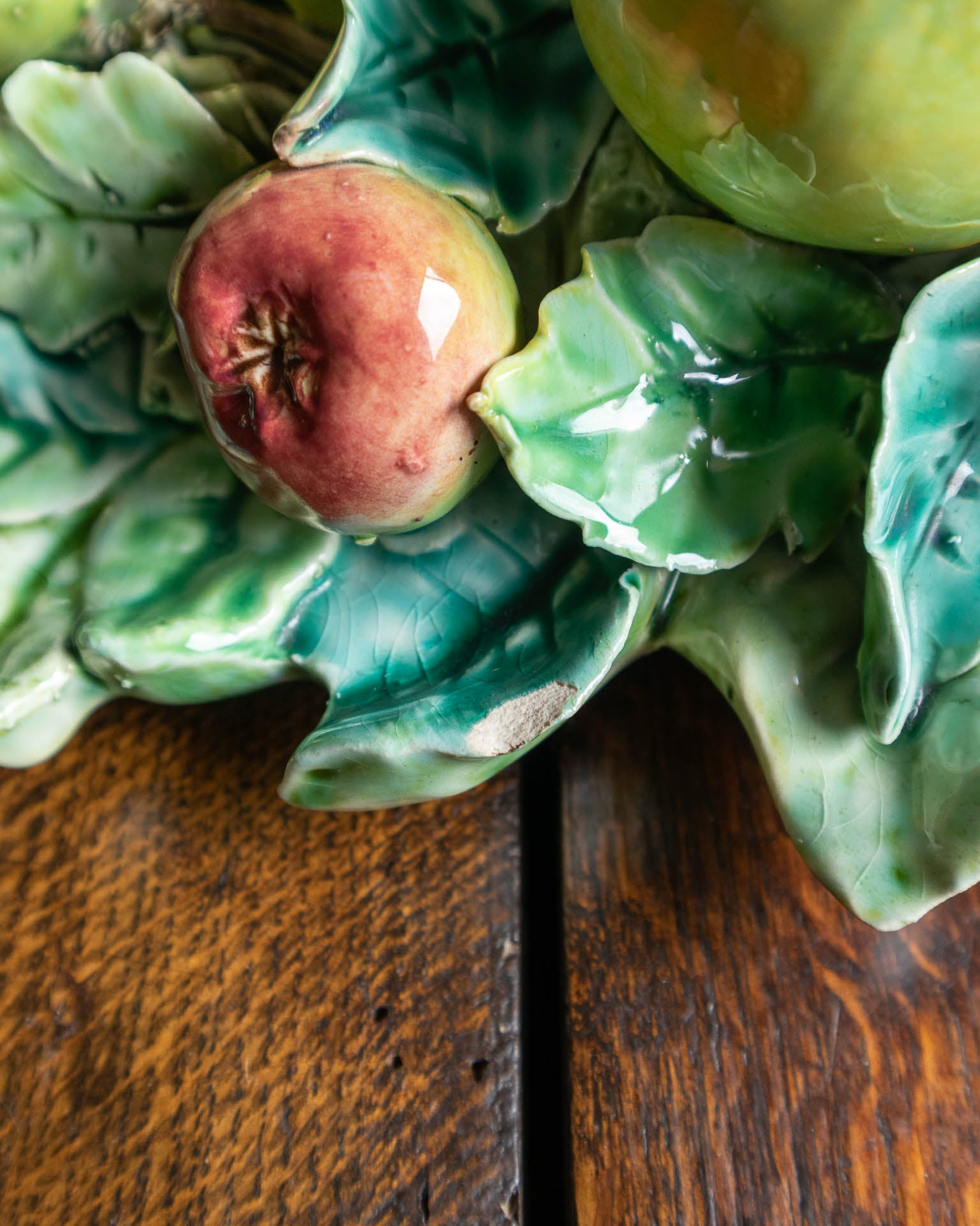 Decorative ceramic piece with apples and leaves on a wooden surface