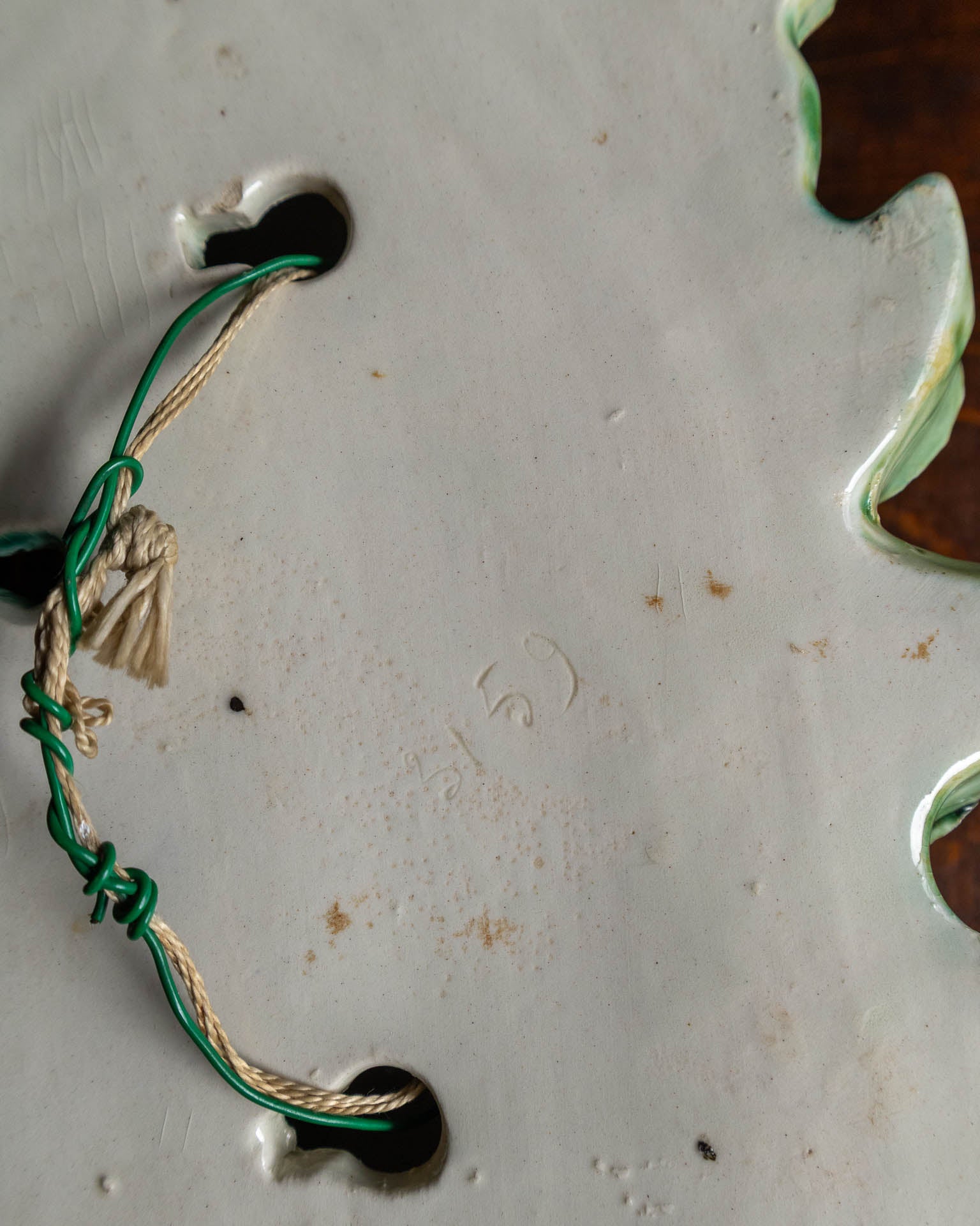 Close-up of a green and beige cord on a ceramic surface