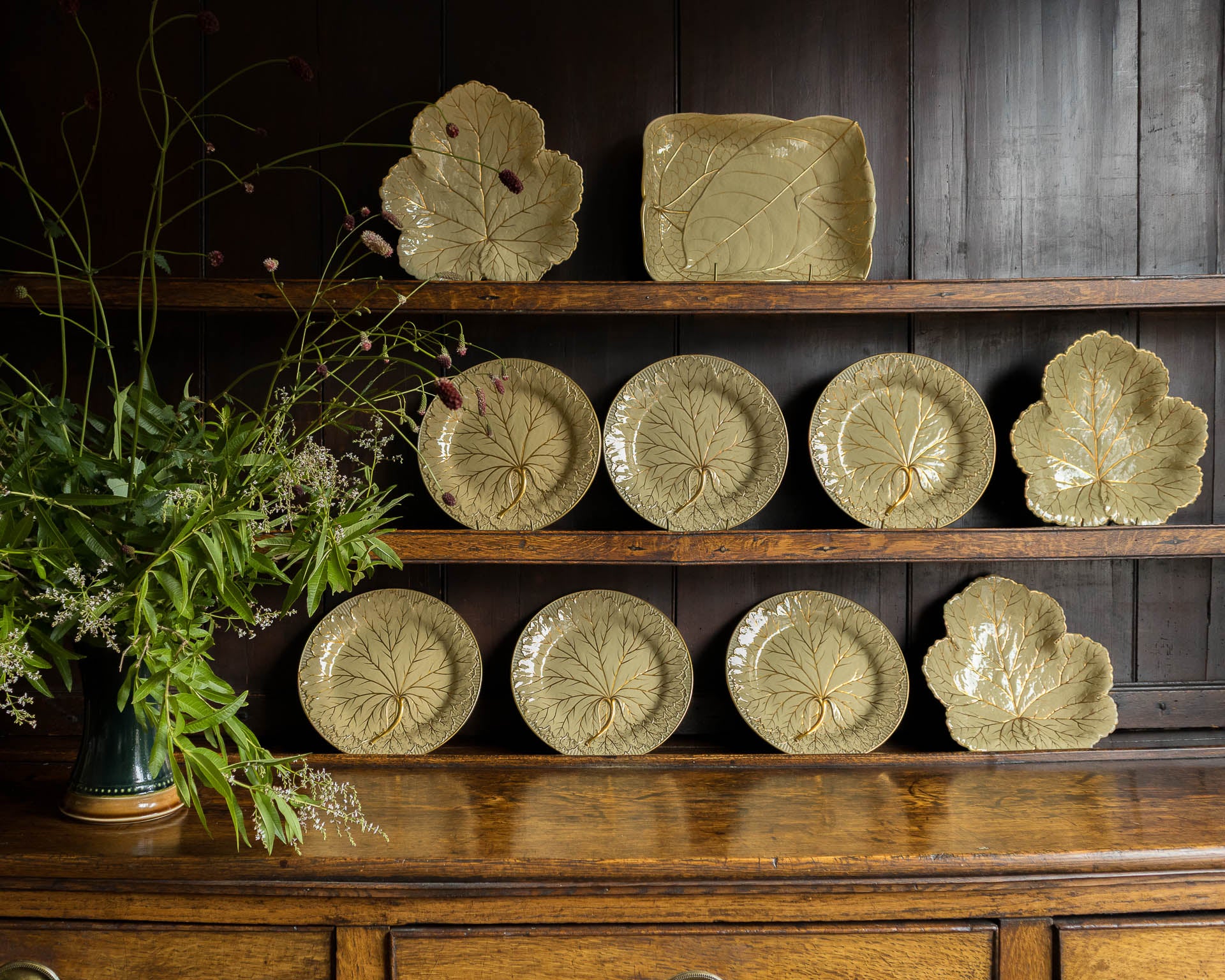Collection of Wedgwood ceramic plates on a wooden shelf with a dark background